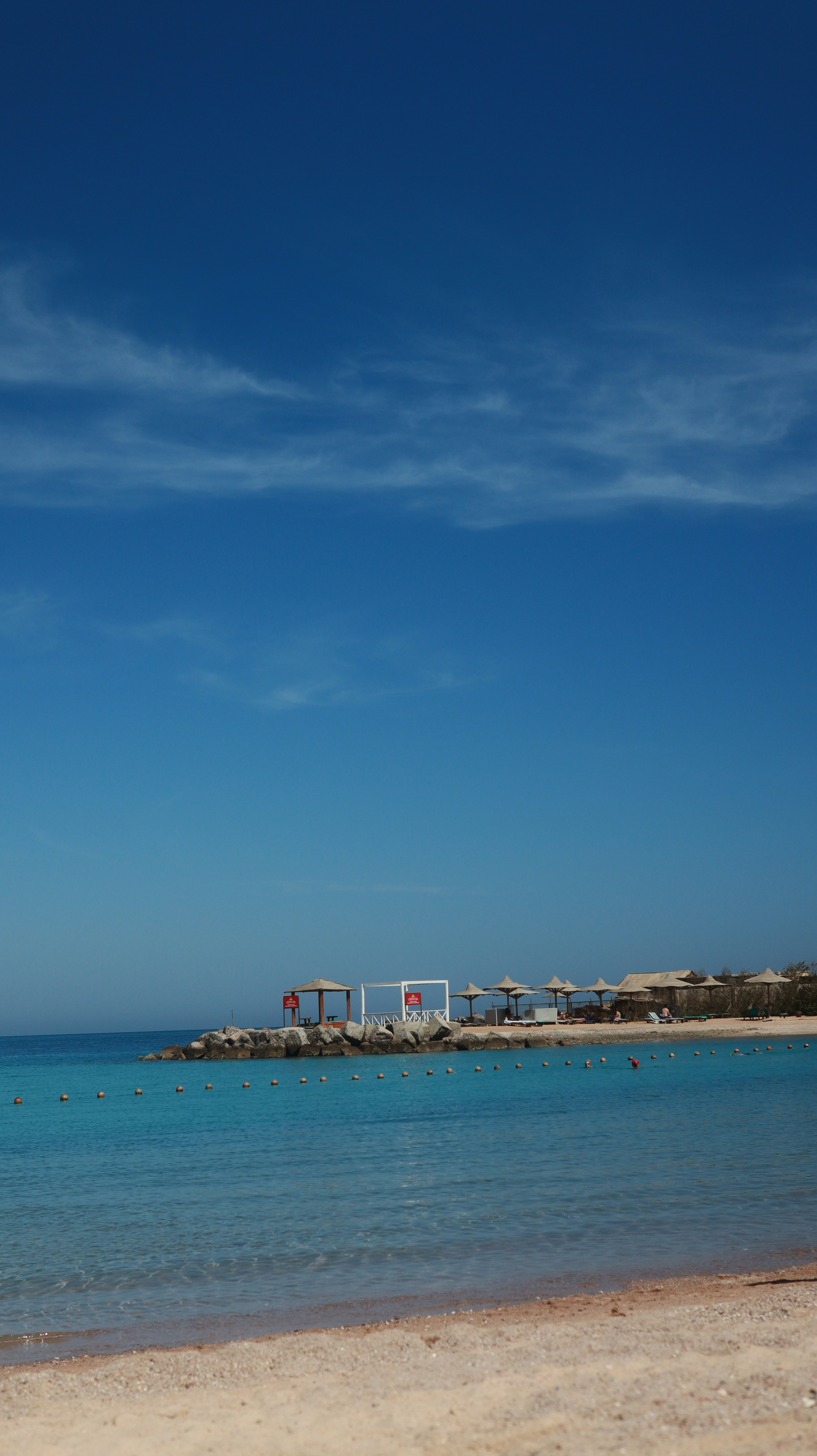 Beach with clear water and a blue sky.