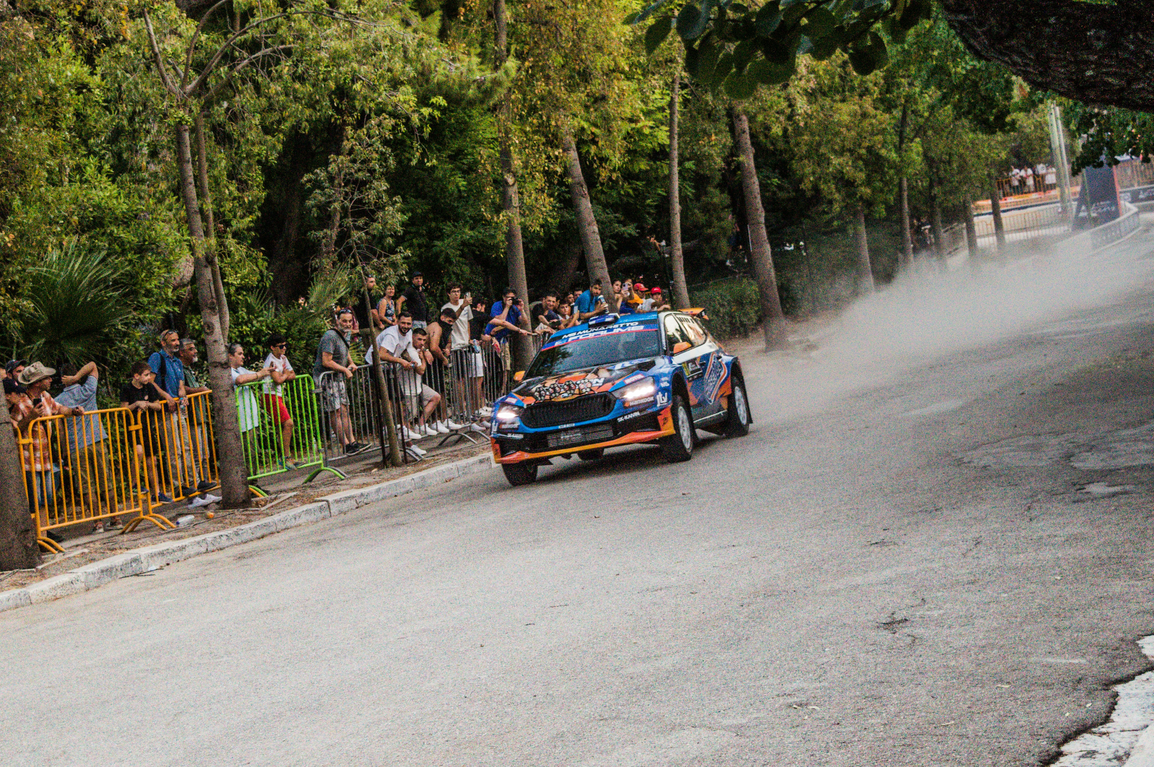 A rally car speeds down a dusty road.