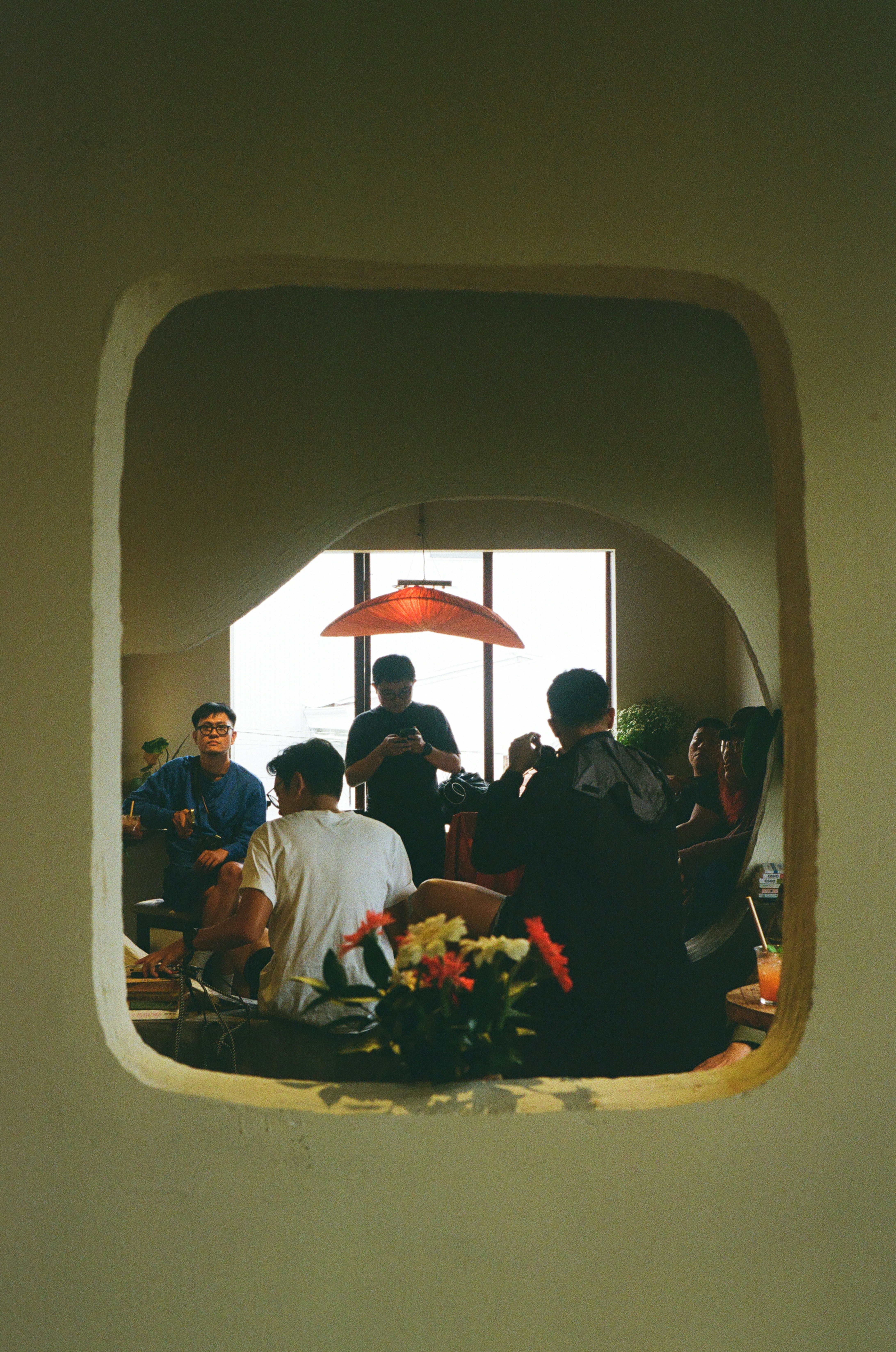 People gather inside a room seen through a window.