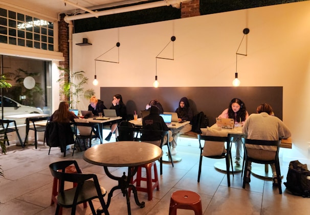 People work on laptops in a cozy coffee shop.