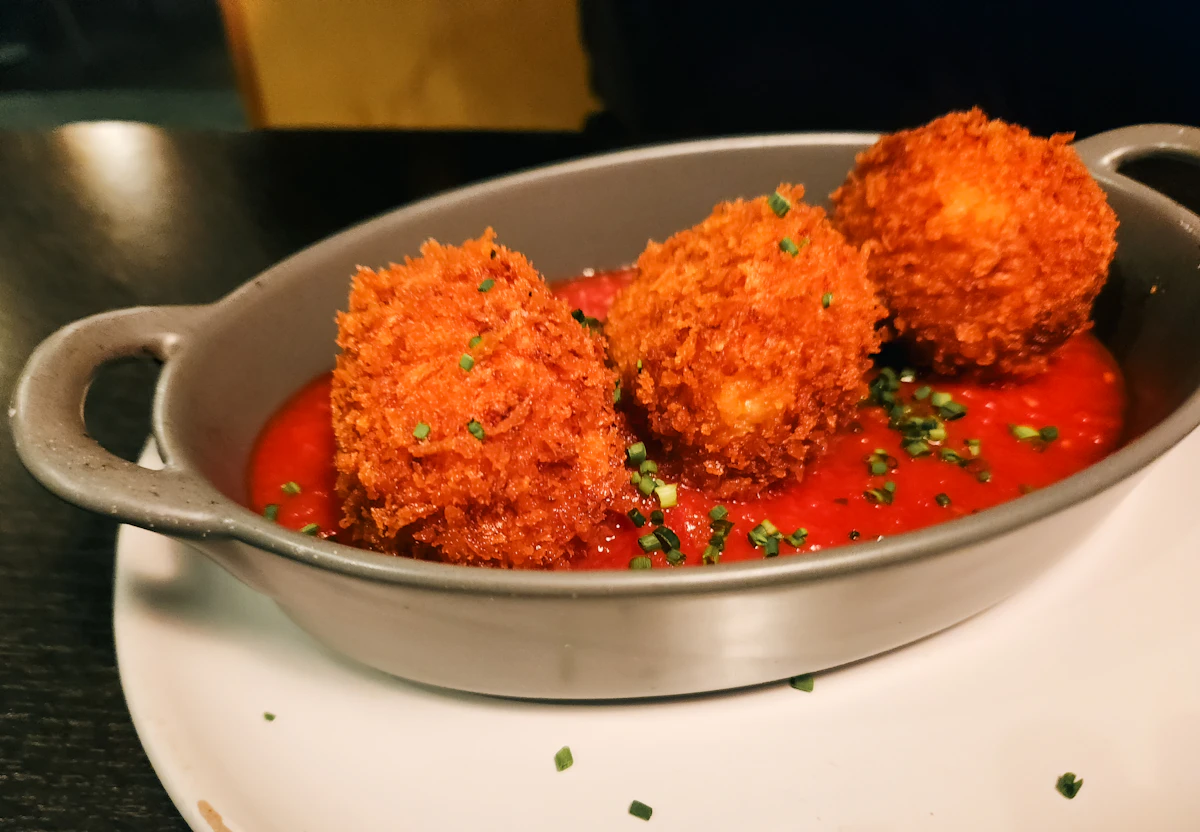 Golden, hand-rolled arancini plated with bright tomato sauce.