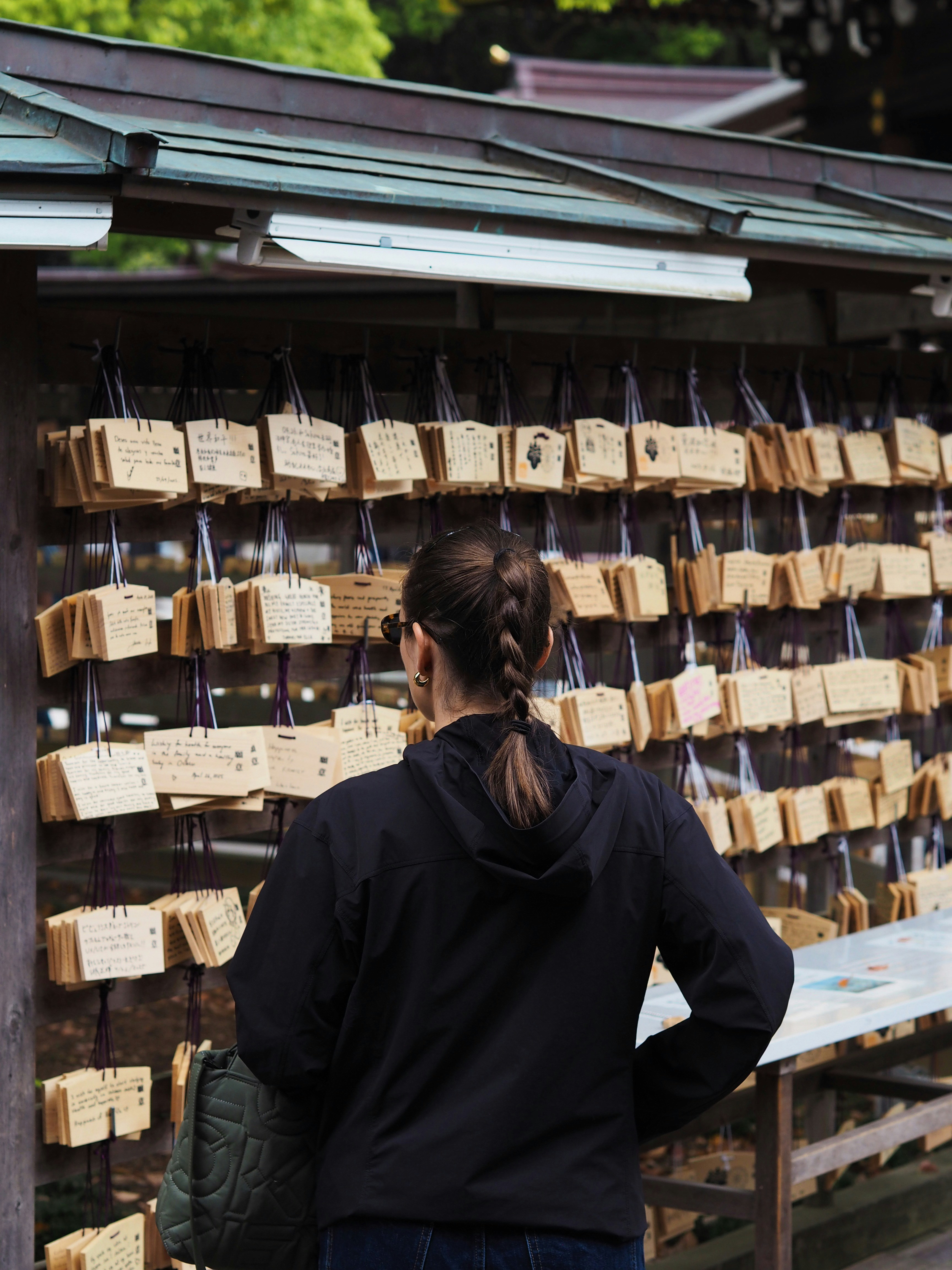 Una donna guarda le tavolette di preghiera su un muro.