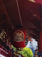 A red lantern hangs from a traditional japanese structure.