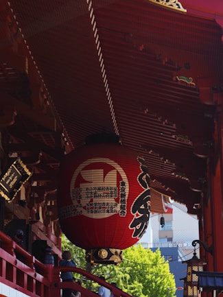 A red lantern hangs from a traditional japanese structure.