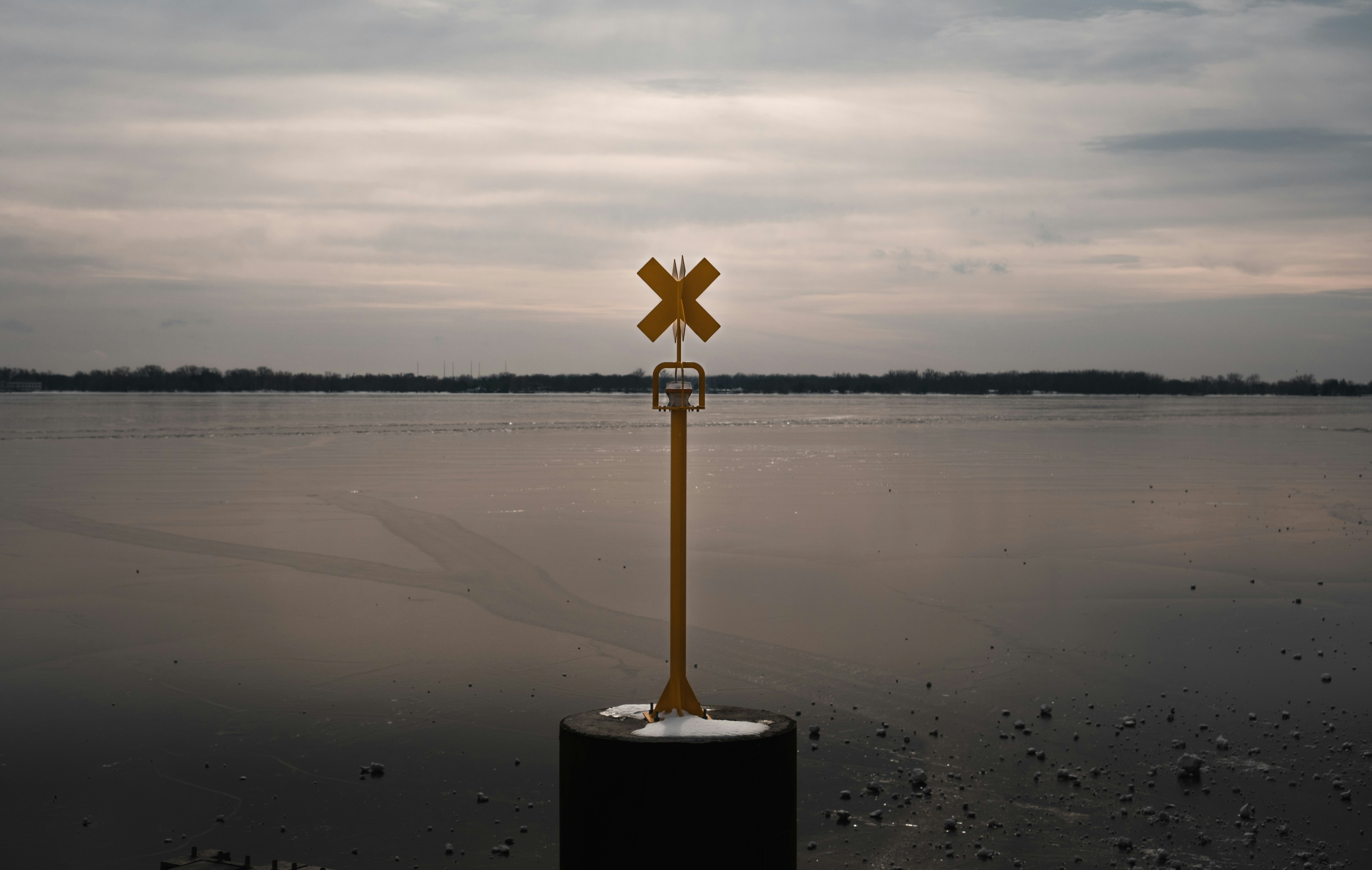 A yellow marker stands against a calm lake.