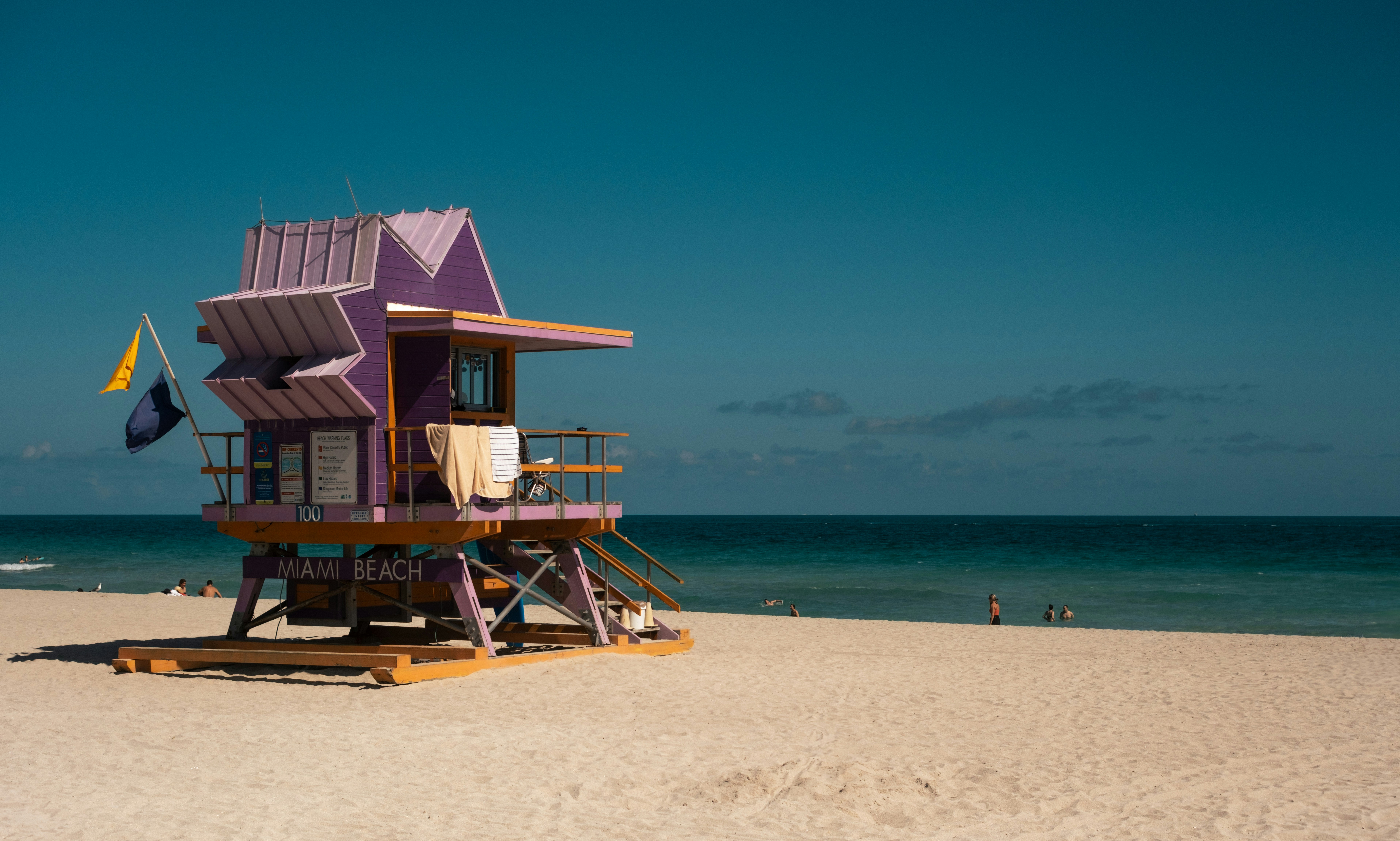 A purple lifeguard stand sits on a sandy beach.