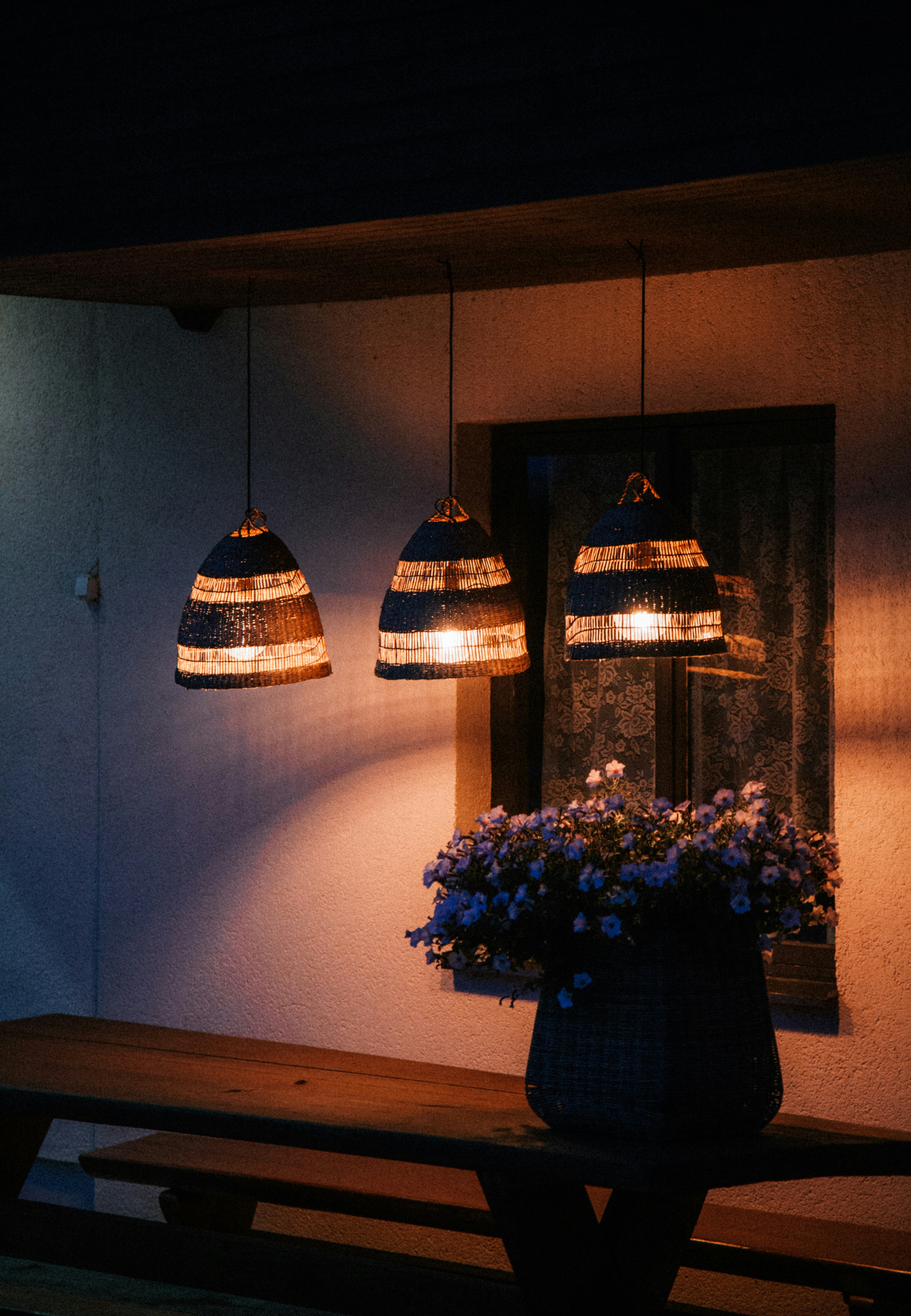 Lit lamps and flowers decorate an outdoor patio.