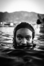 Woman emerges from water, staring directly.