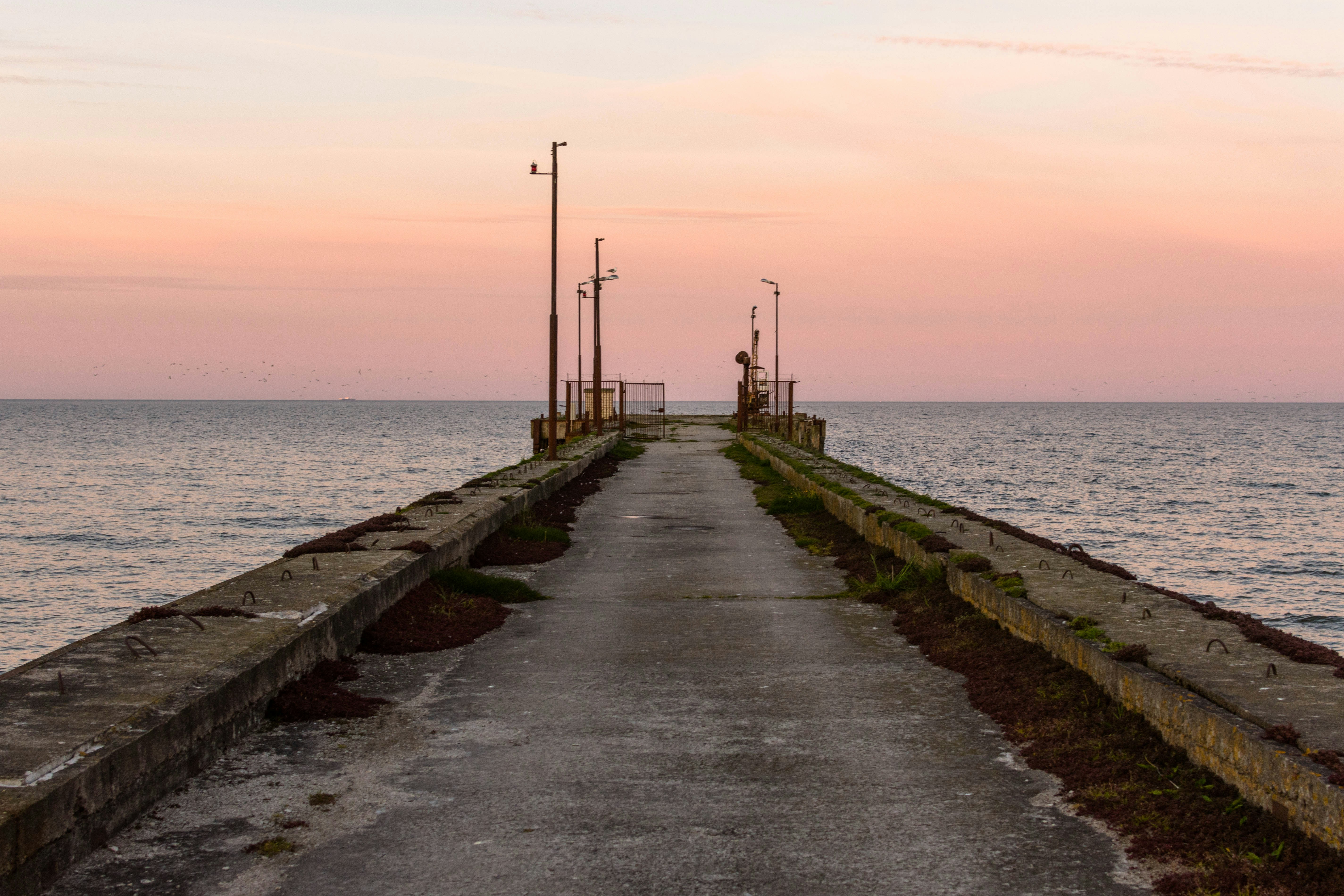 A concrete pier stretches towards the peaceful sea.