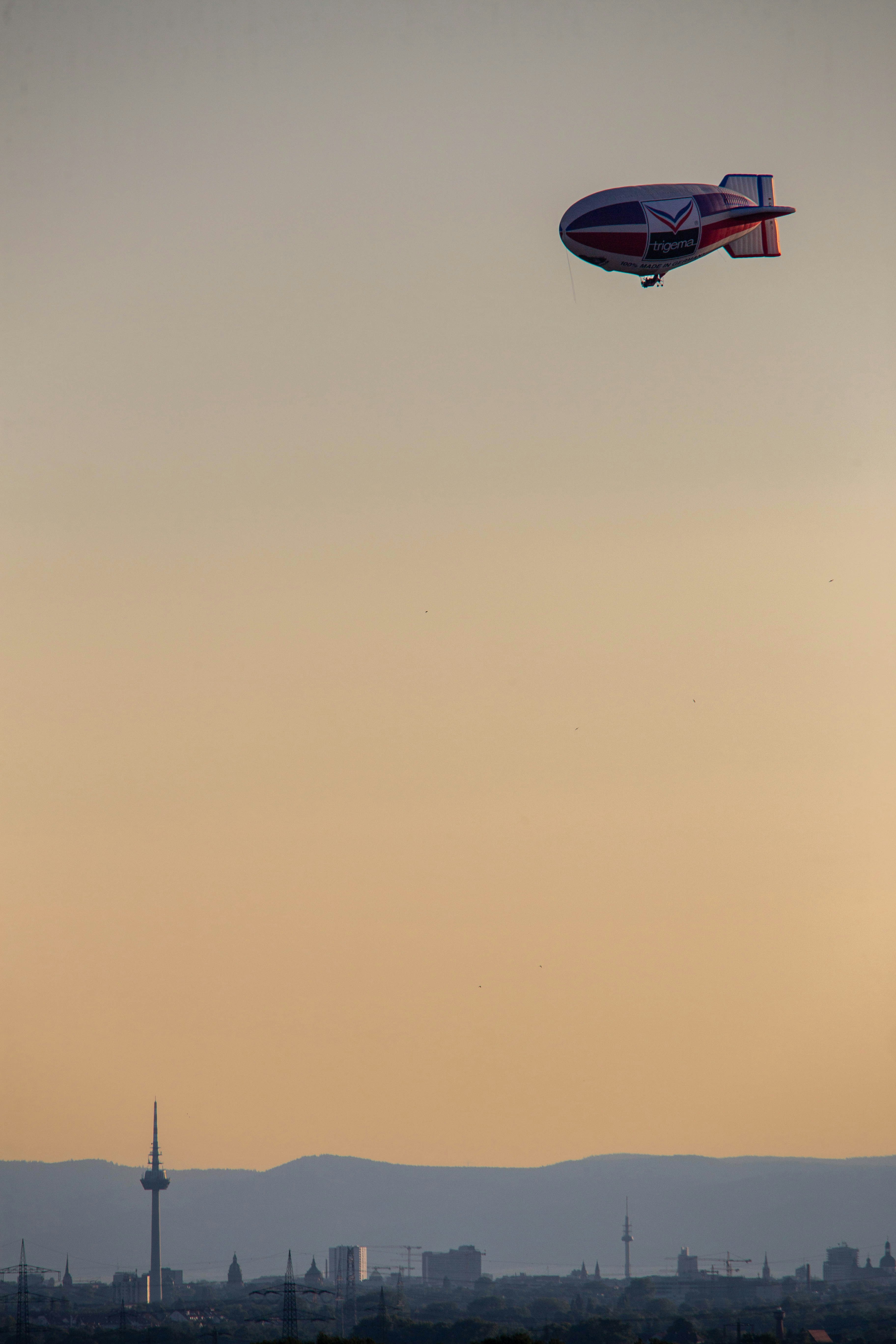 An airship flies over a city skyline.