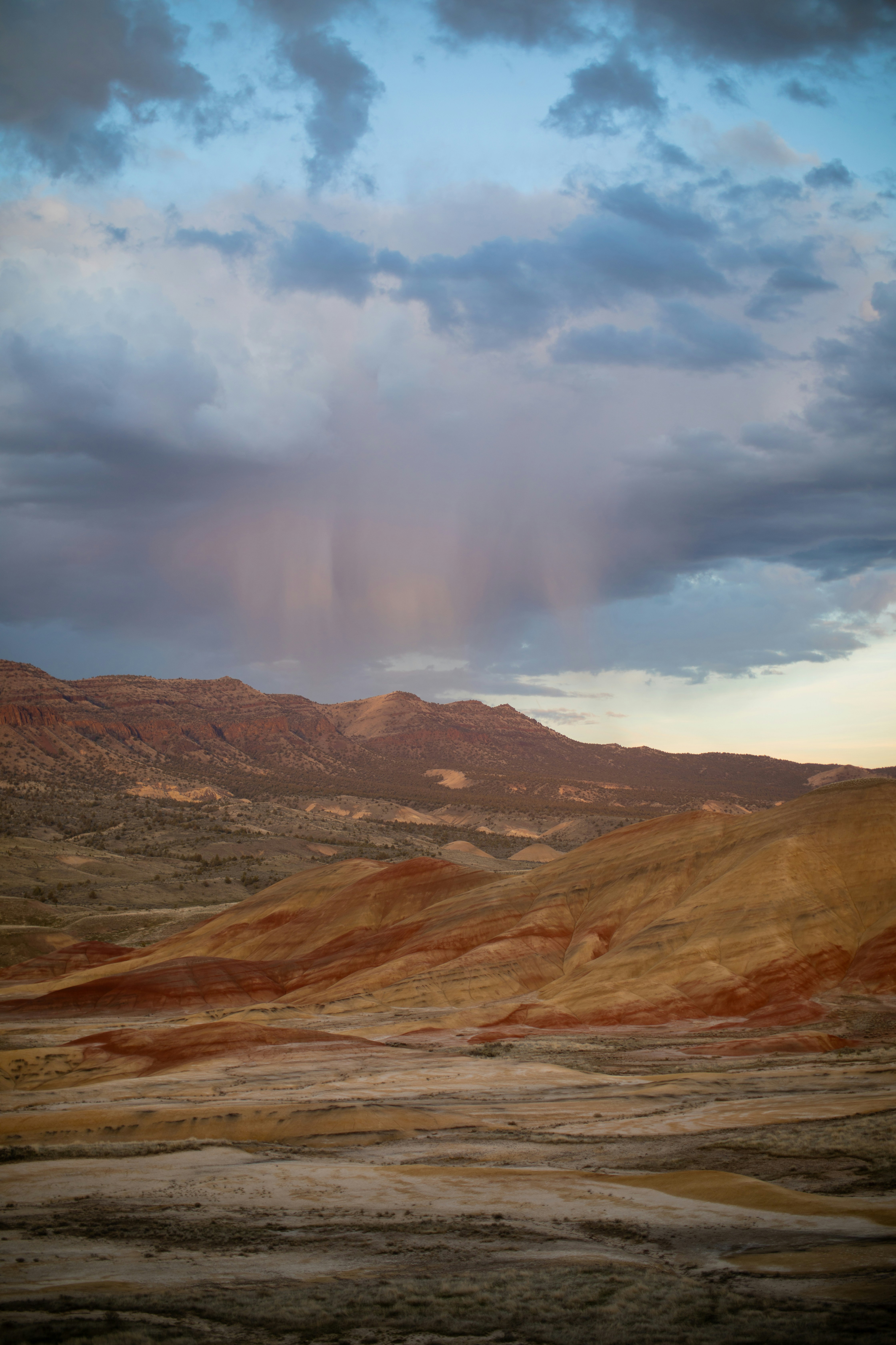 Rain showers fall over a colorful desert landscape.