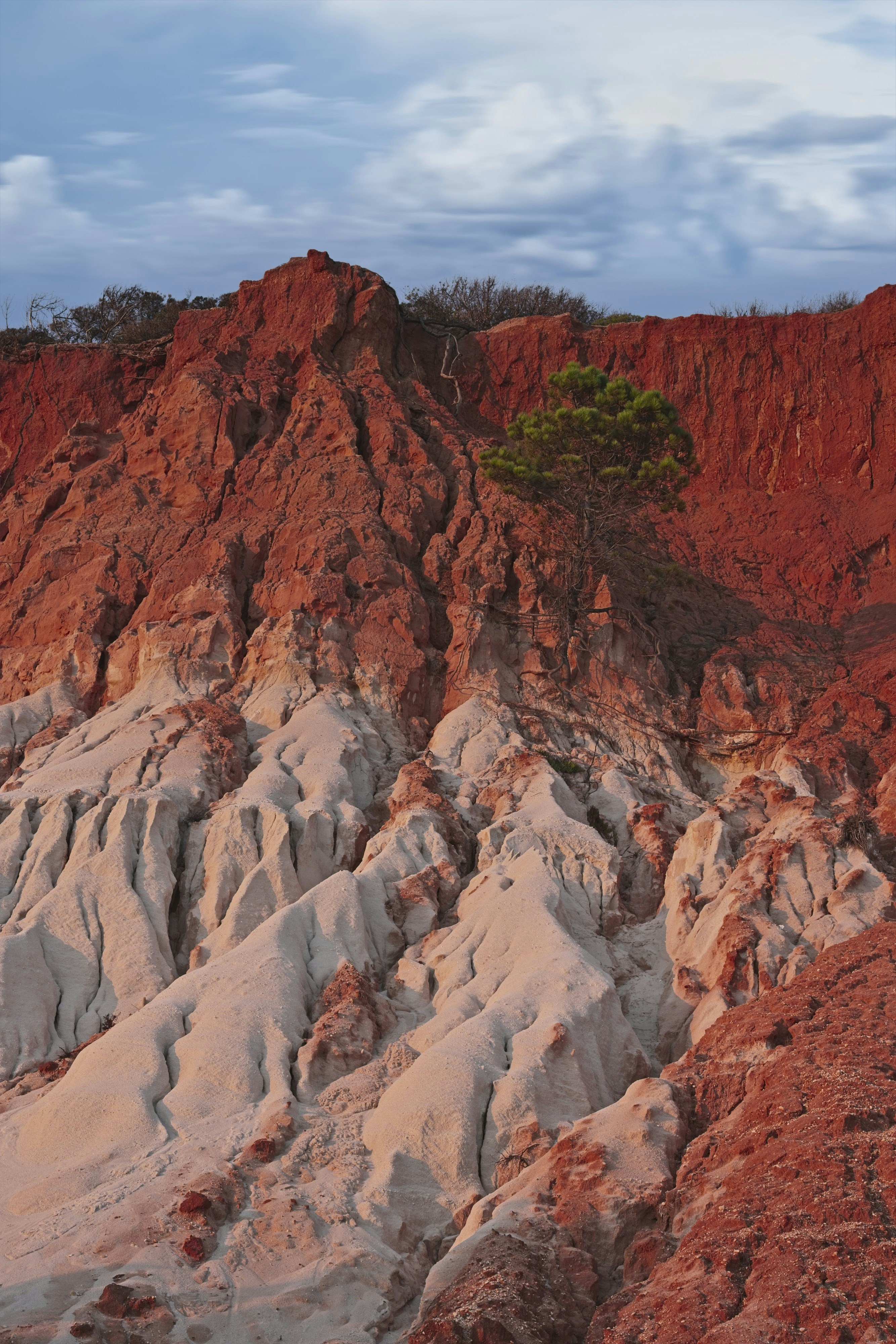 Tebing merah menjulang di atas bebatuan putih berukir.