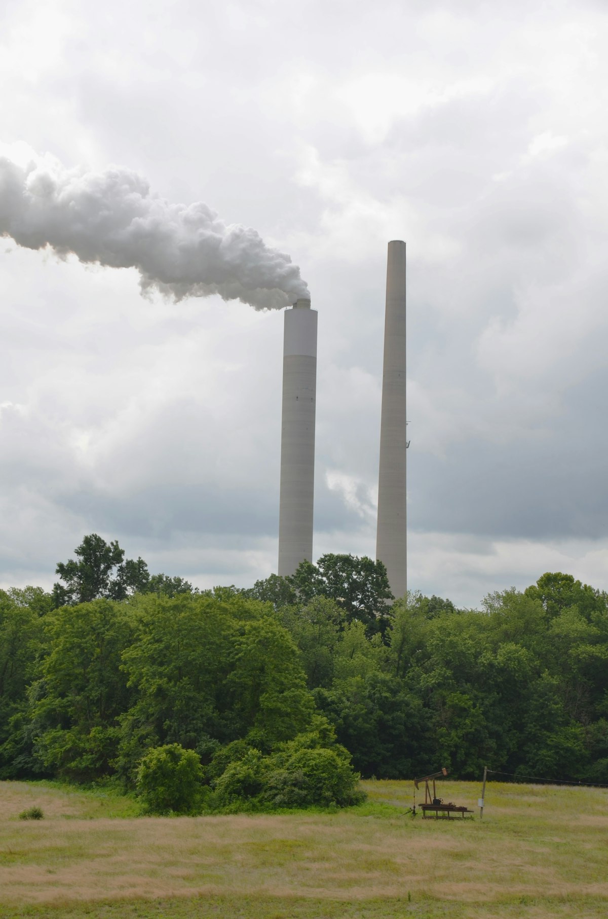 Industrial coal power plant with smokestacks and cooling towers against a cloudy sky