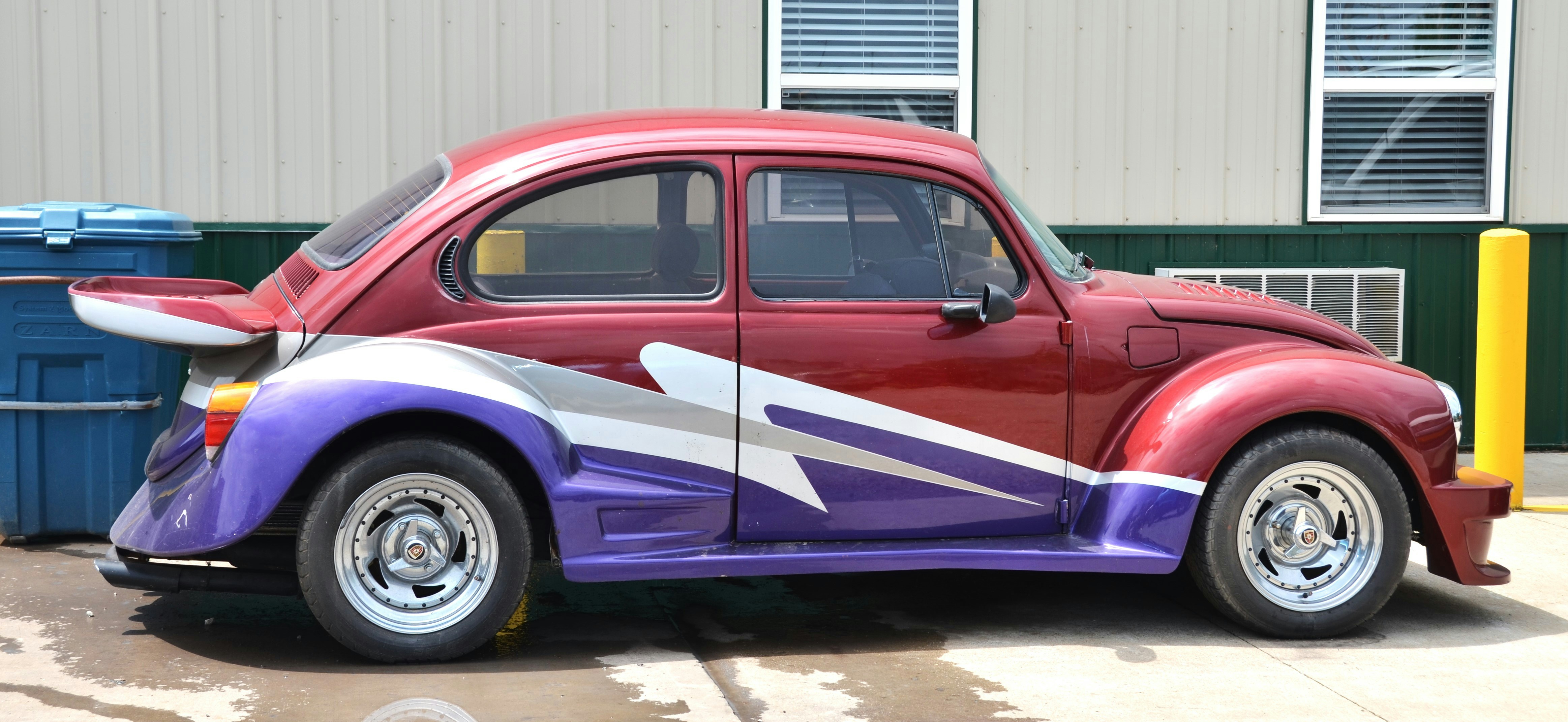 A modified Volkswagen Beetle featuring a multi-tone design with custom car paint colours in metallic red and purple.