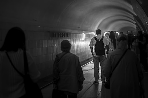 People walk through a dimly lit, curved tunnel.