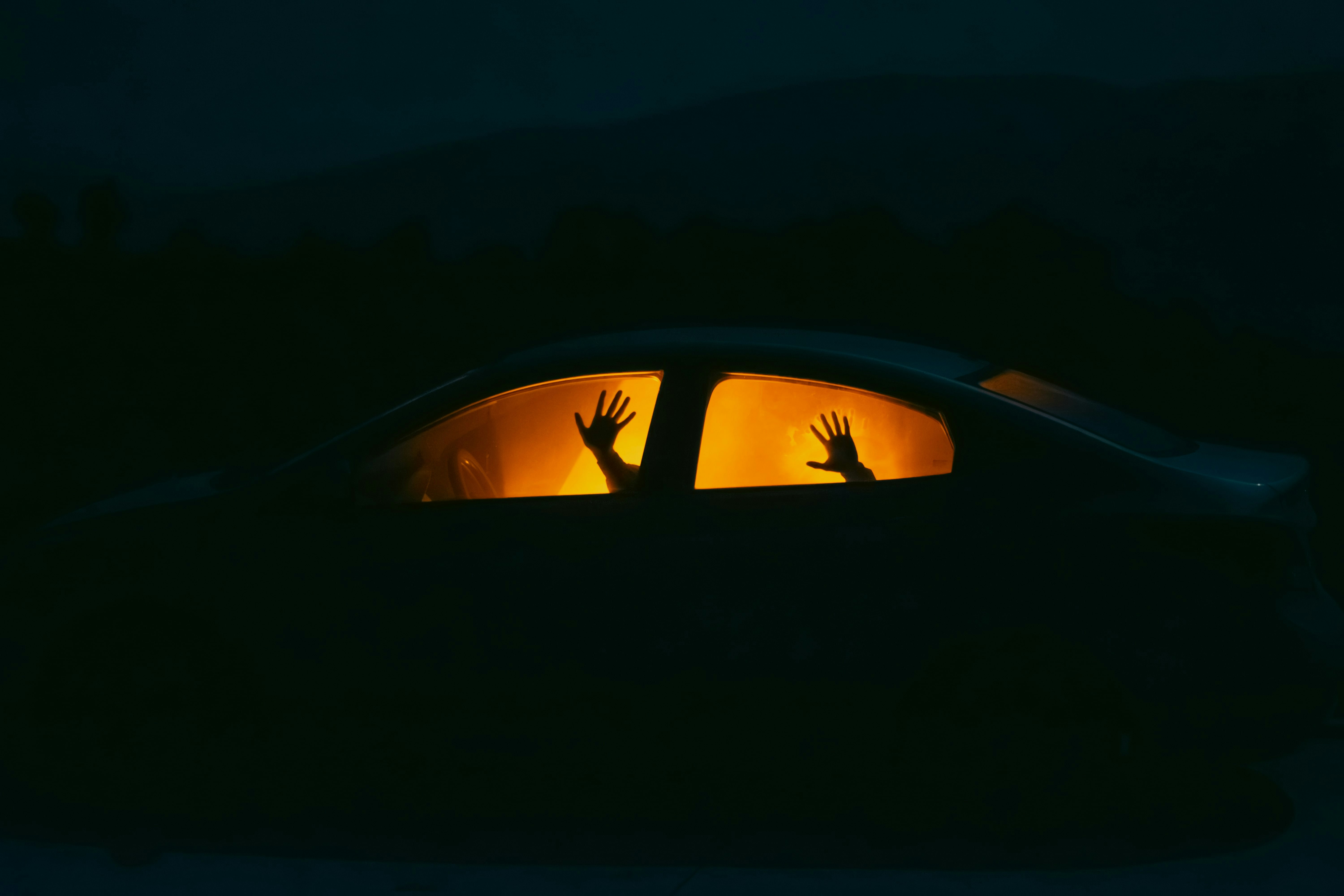 Hands reach out of a car window at night.