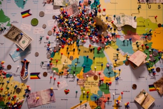 A world map is covered with pins and mementos.