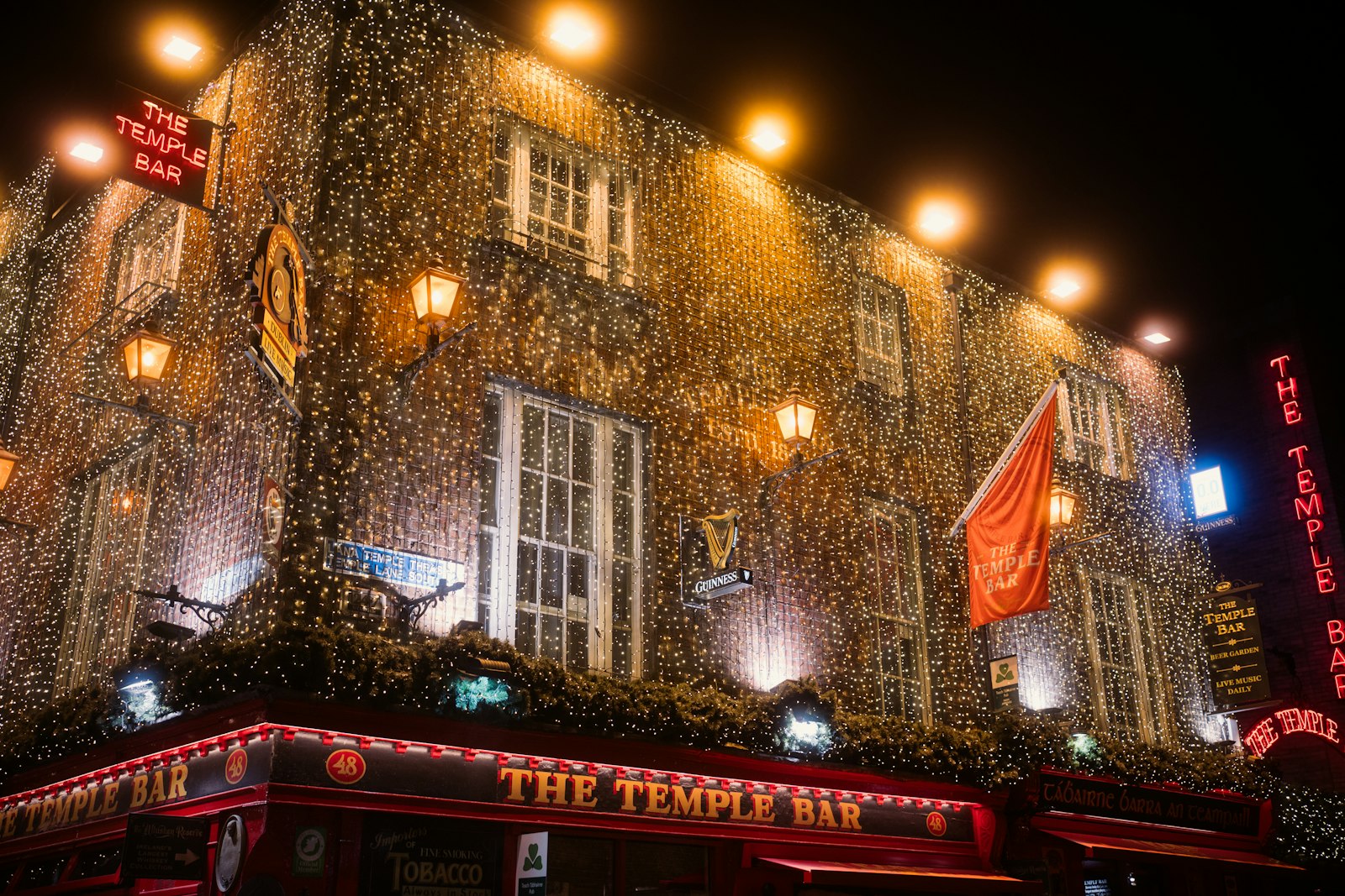 Dublin's Temple Bar district glowing with string lights at night, near Trinity College and the River Liffey