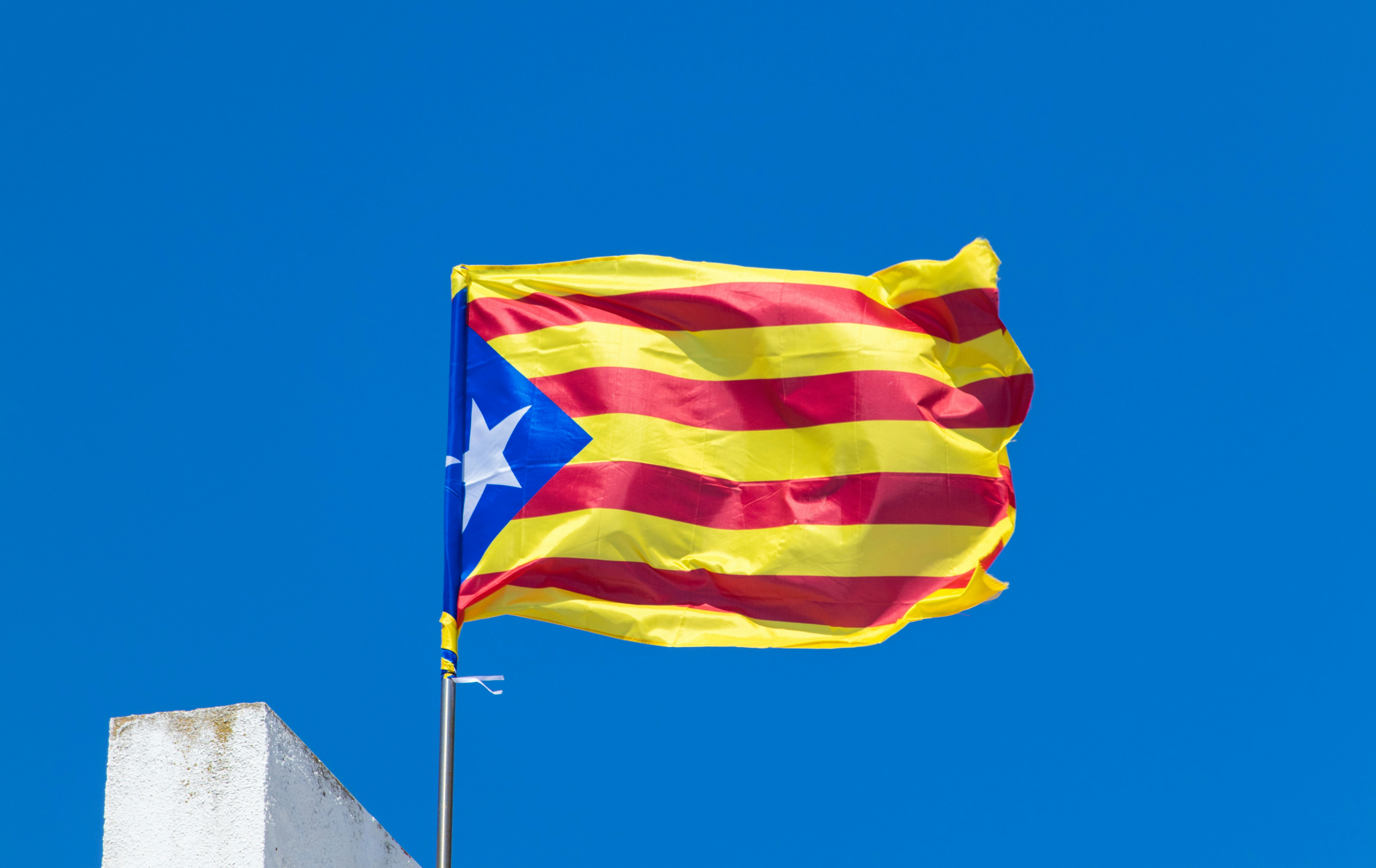 A catalan flag flies proudly against a blue sky.