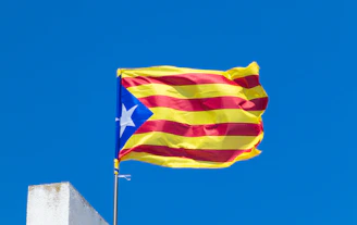 A catalan flag flies proudly against a blue sky.