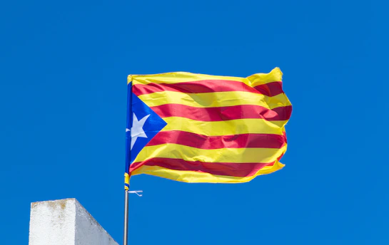 A catalan flag flies proudly against a blue sky.