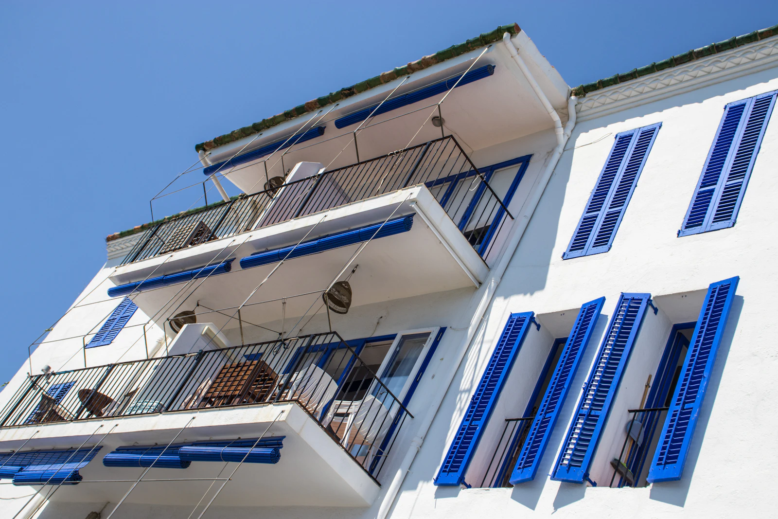 Sunlit white Mediterranean building with blue shutters