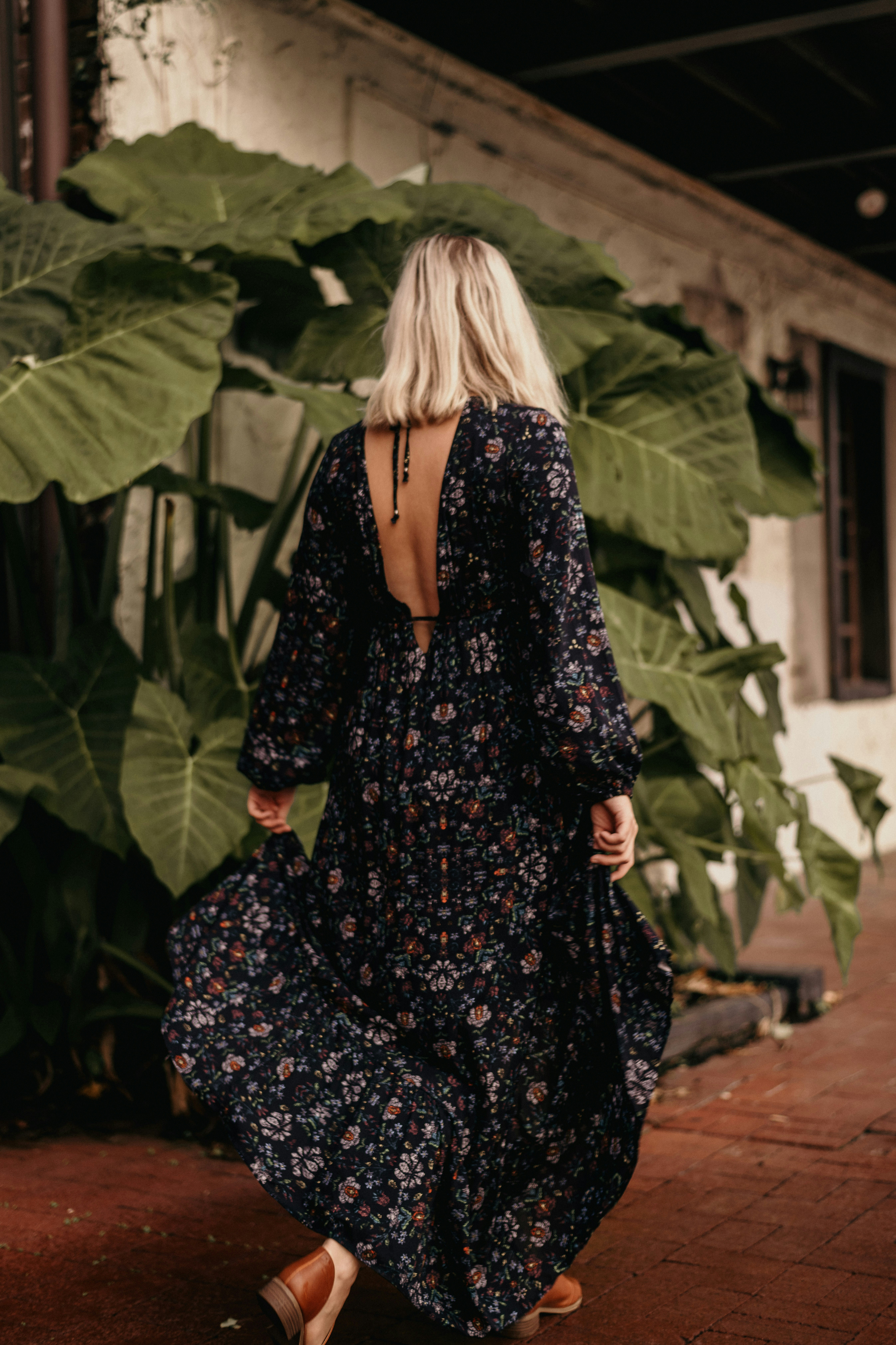 Woman in floral dress walks away, outdoors.