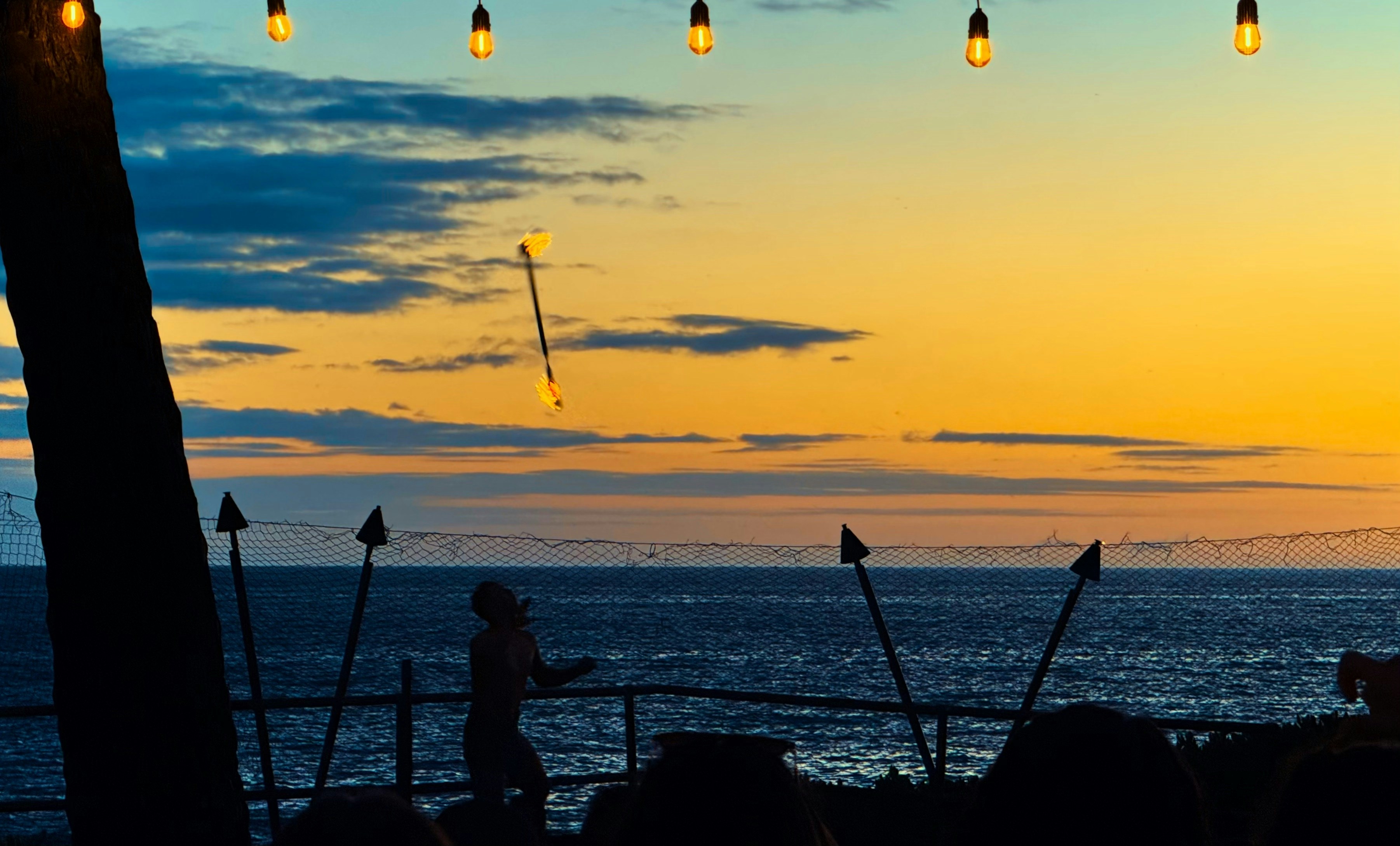 A sunset view with torches and ocean.