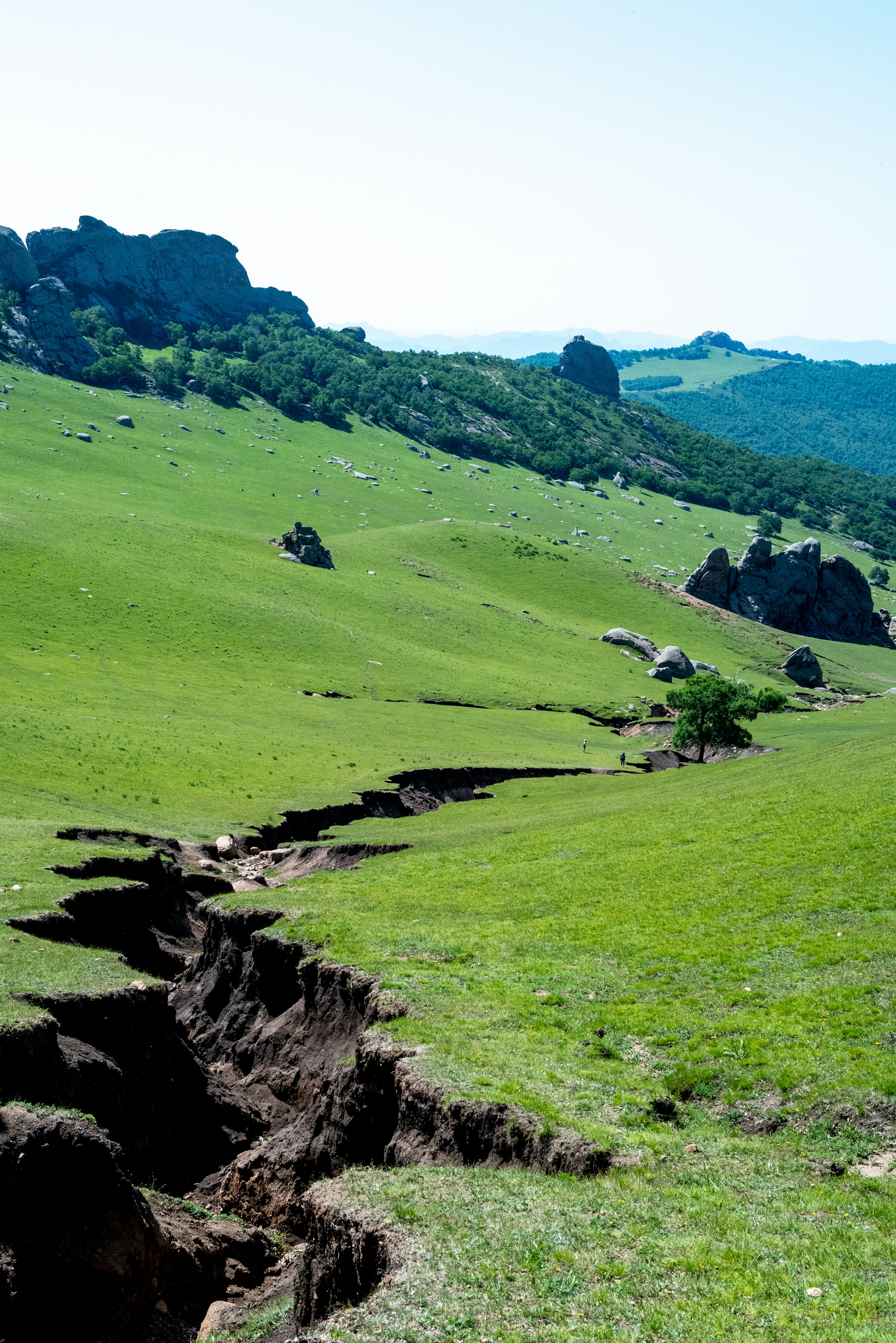 A green hillside is divided by a deep gorge. photo – Free Image on Unsplash