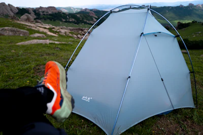 Camping tent pitched amidst grassy terrain.