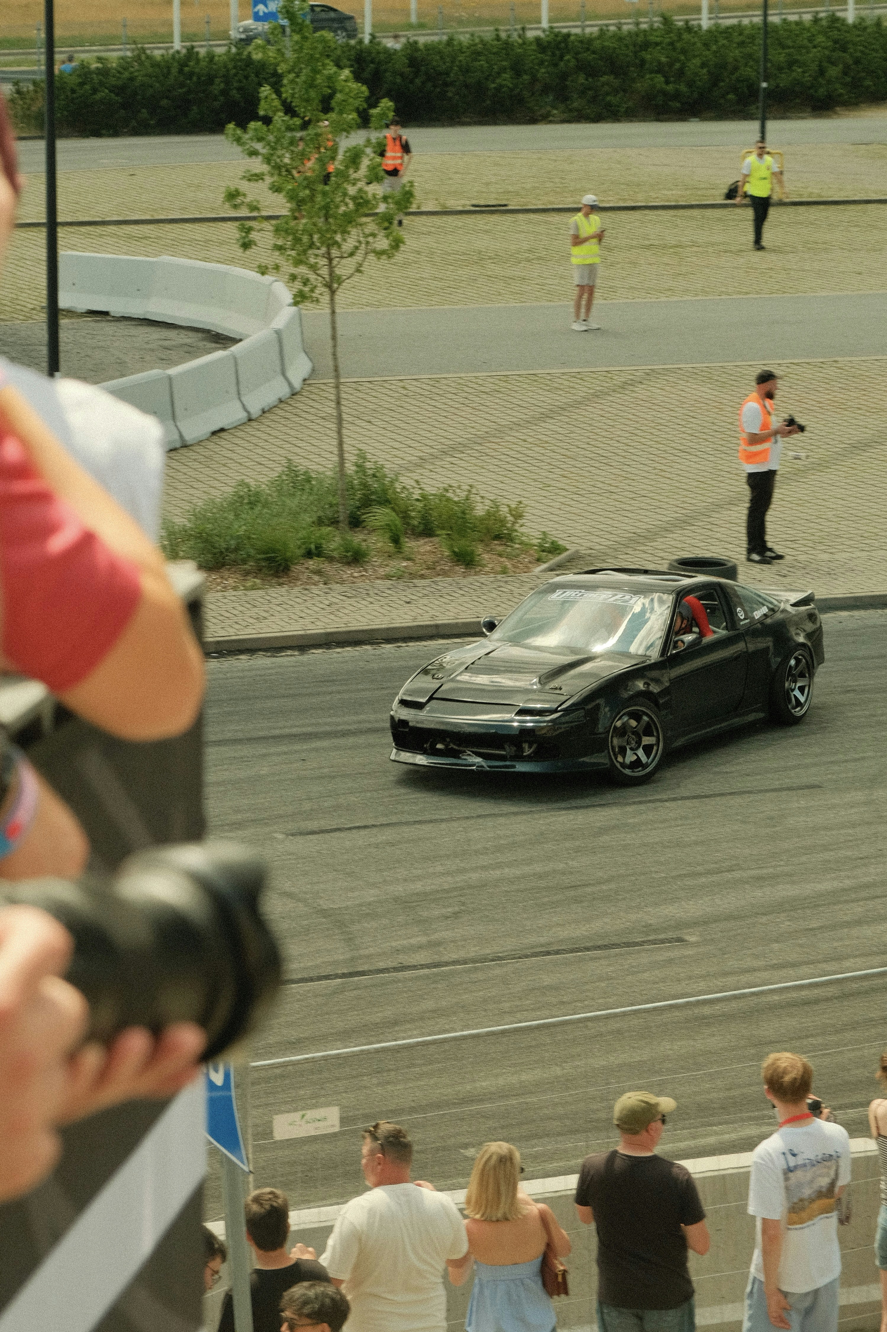 A black car drifts at a racetrack.