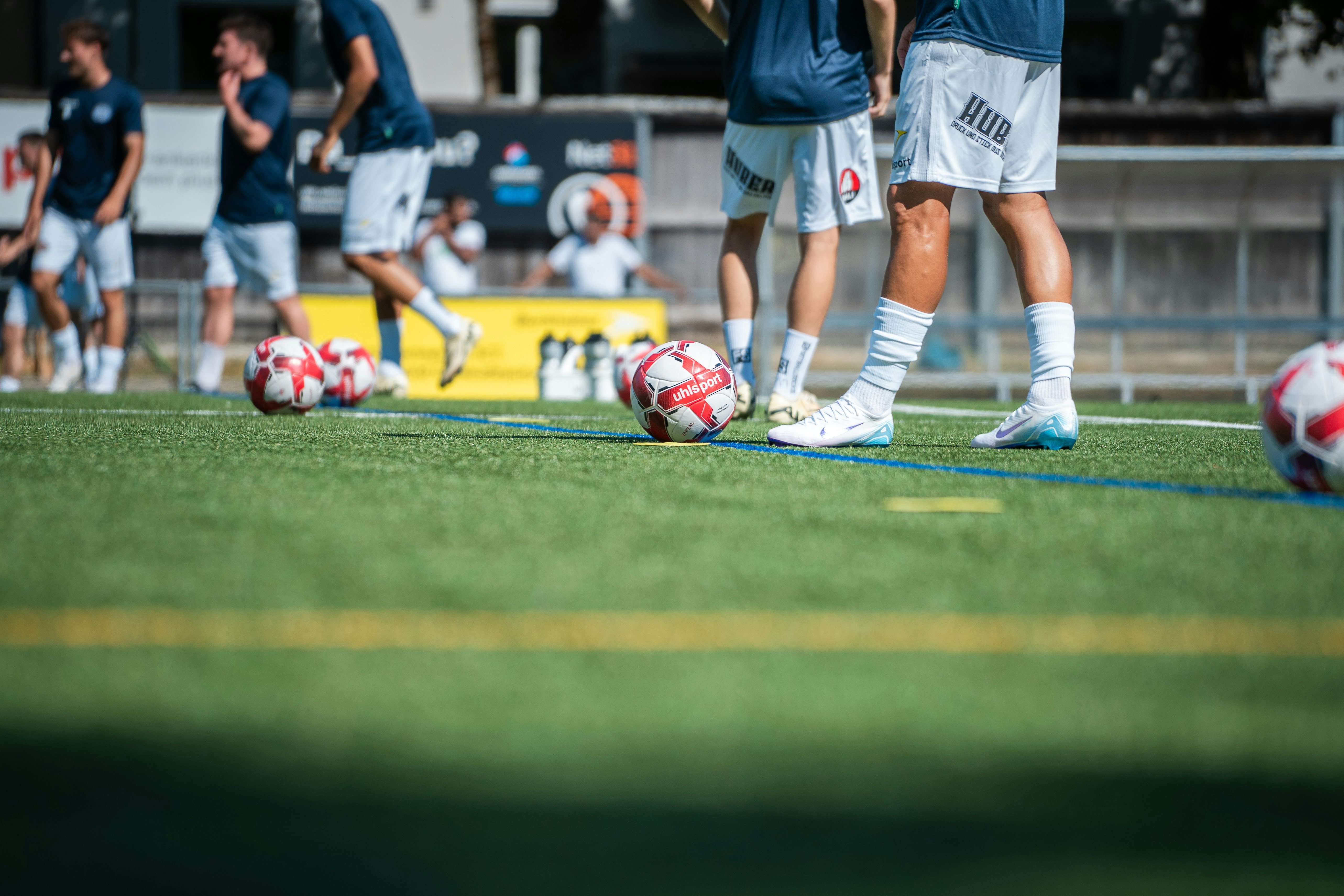 Soccer players are on the field with soccer balls.