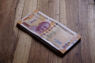 A stack of indian rupees lies on wood.