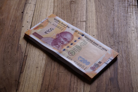 A stack of indian rupees lies on wood.