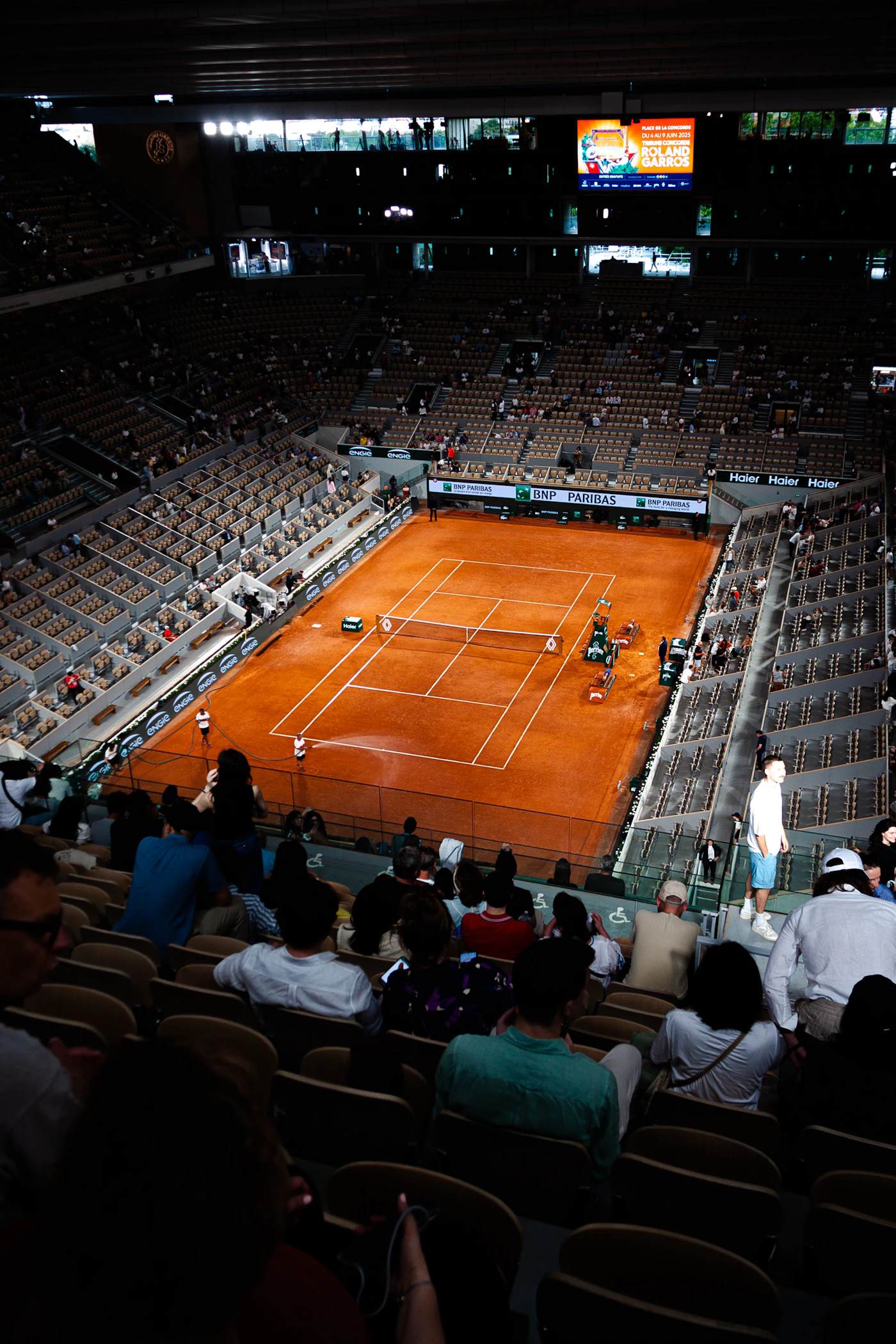A tennis match in a large clay-court arena