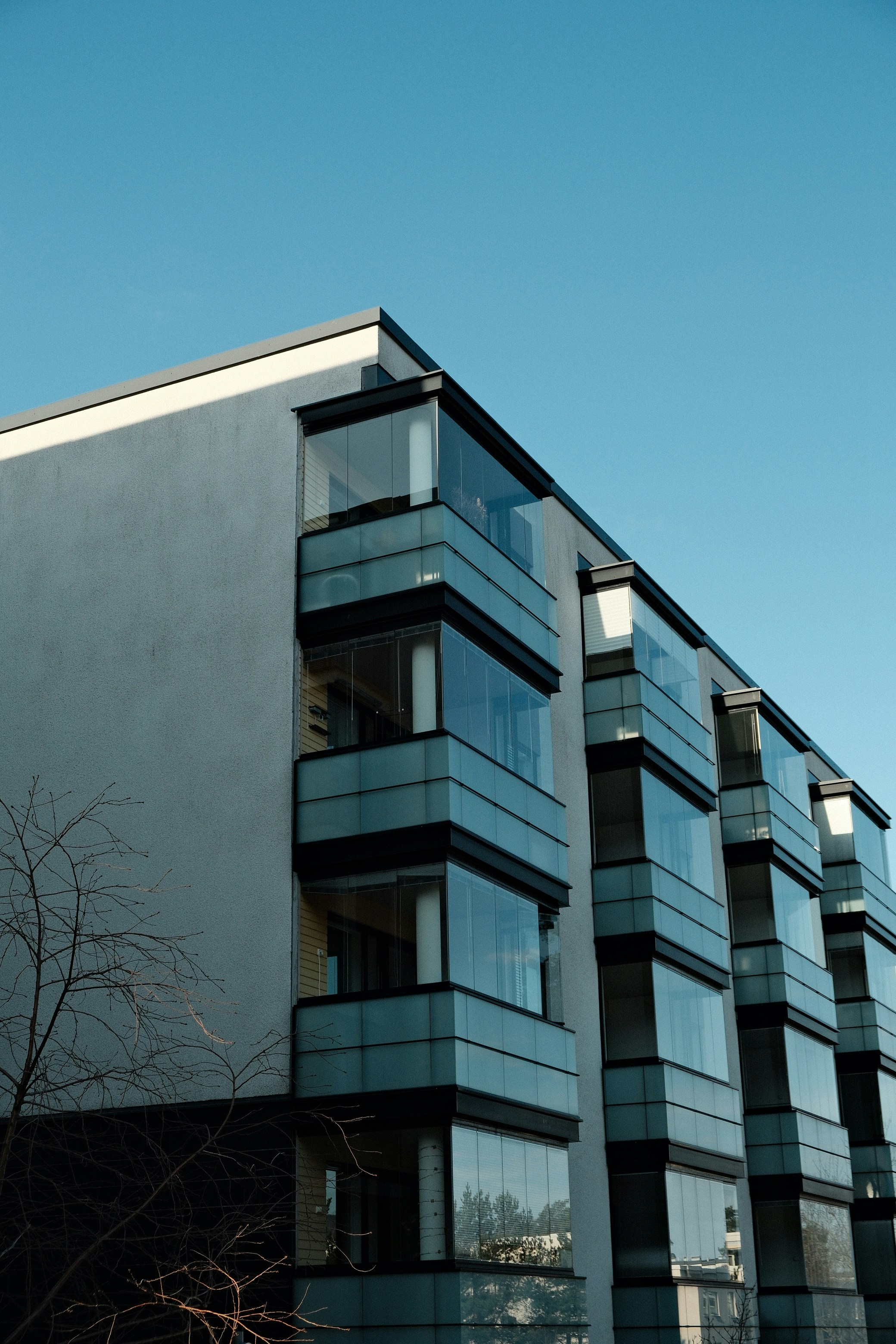 Modernes Mehrfamilienhaus mit Balkonen vor blauem Himmel.