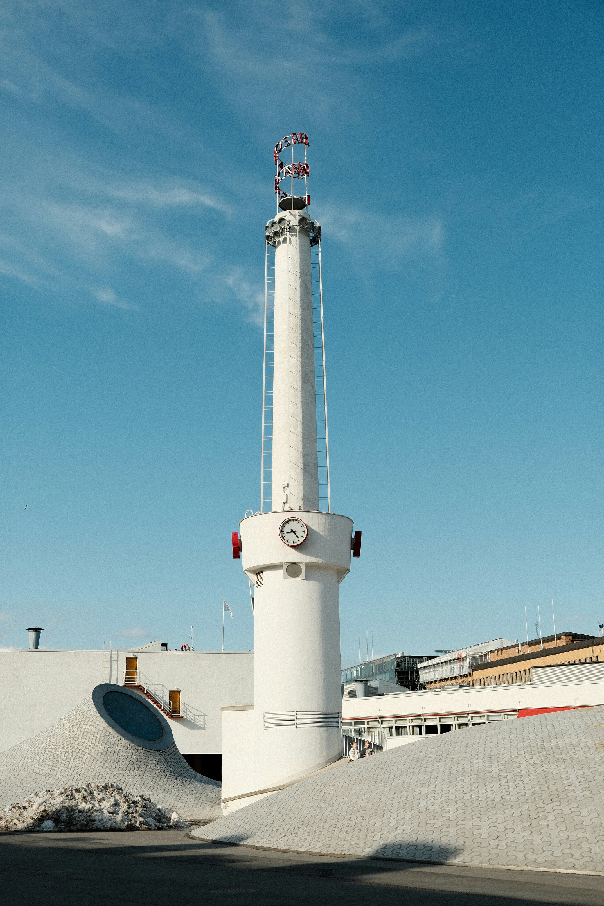 A tall white tower stands under a bright blue sky.