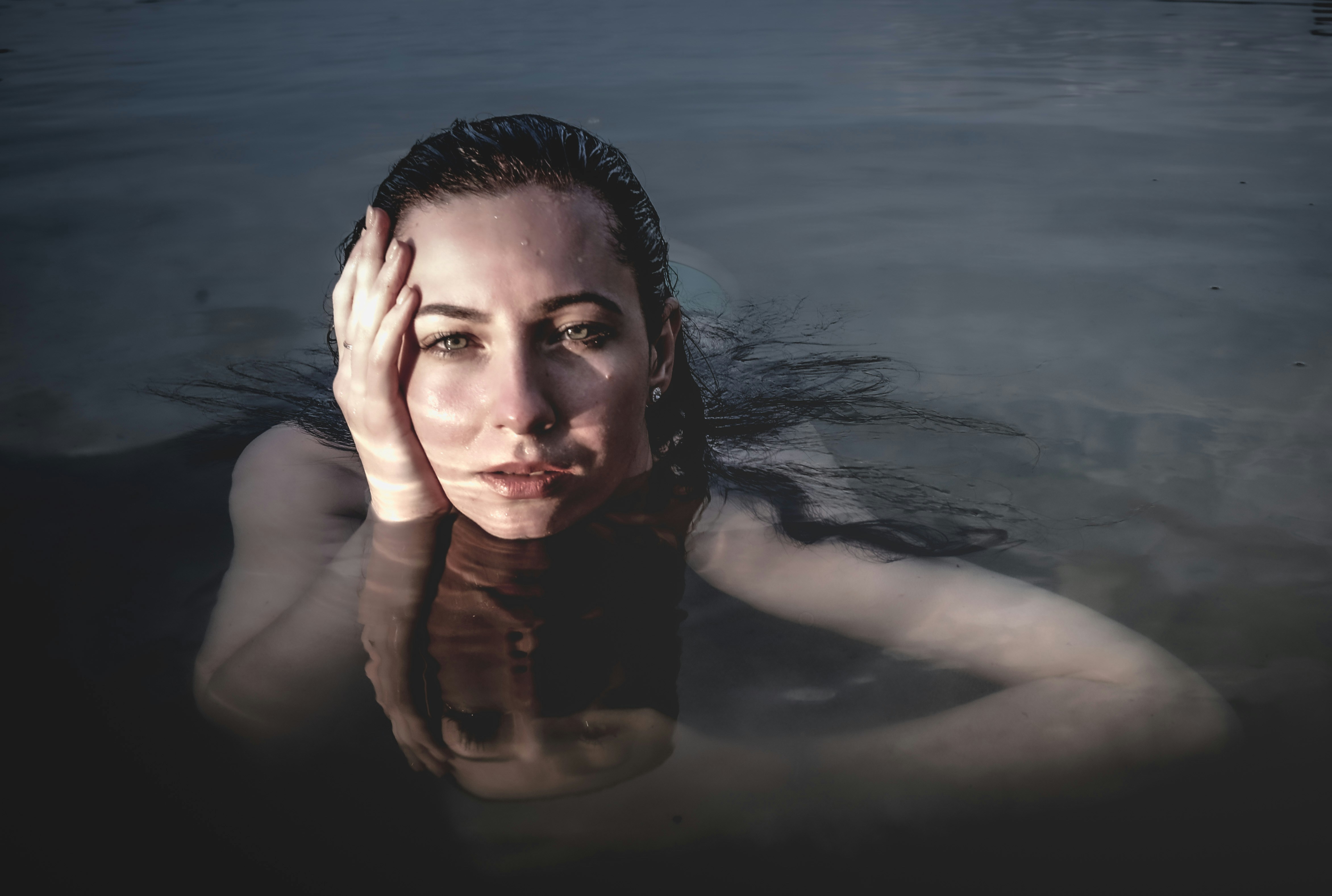 Woman in the water, staring directly at the camera.