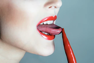 Woman licking a red chili pepper.