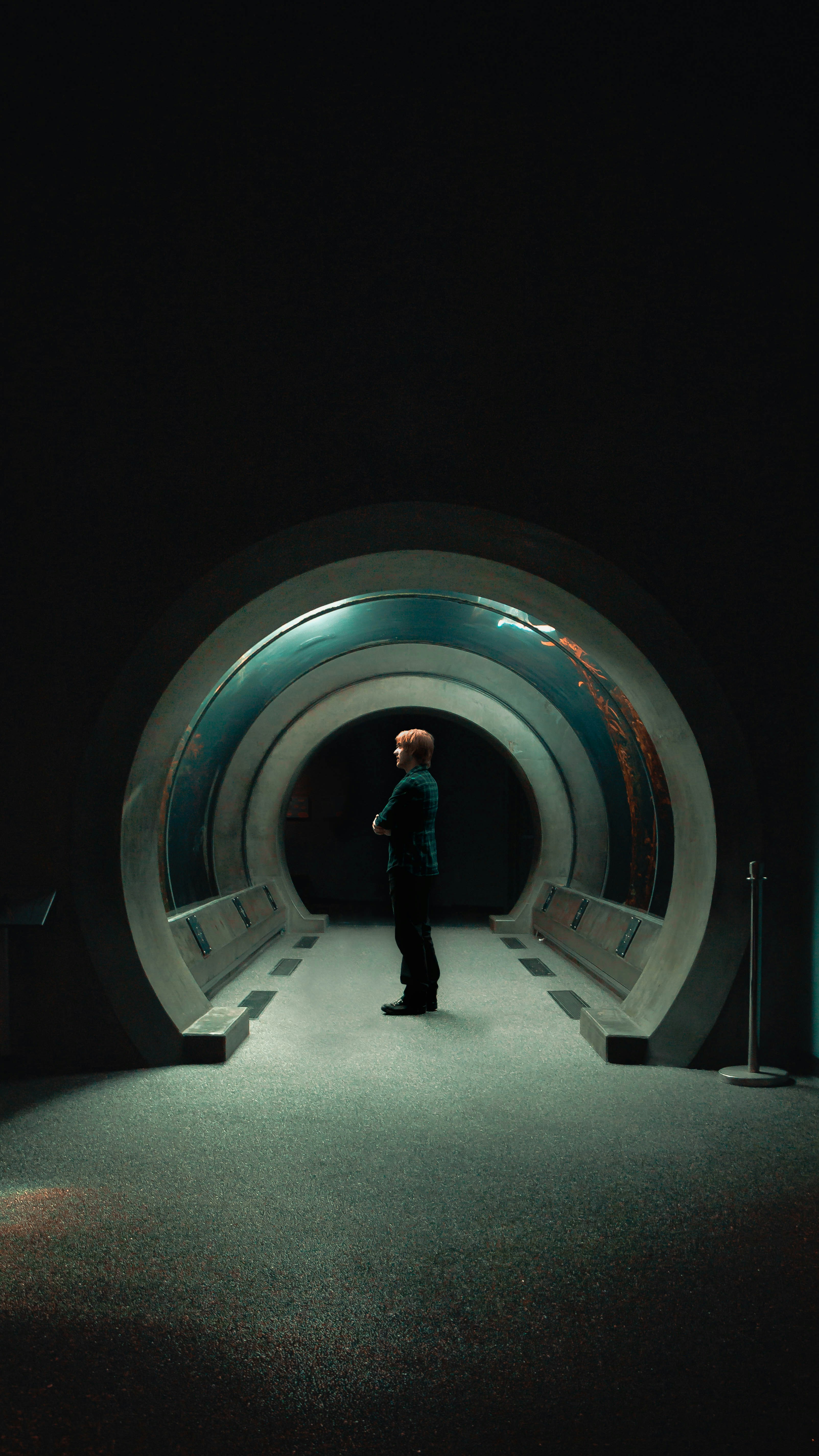 A man stands inside of a circular tunnel.