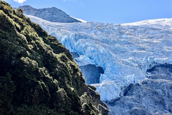 A glacier and green cliffside in a mountainous landscape.