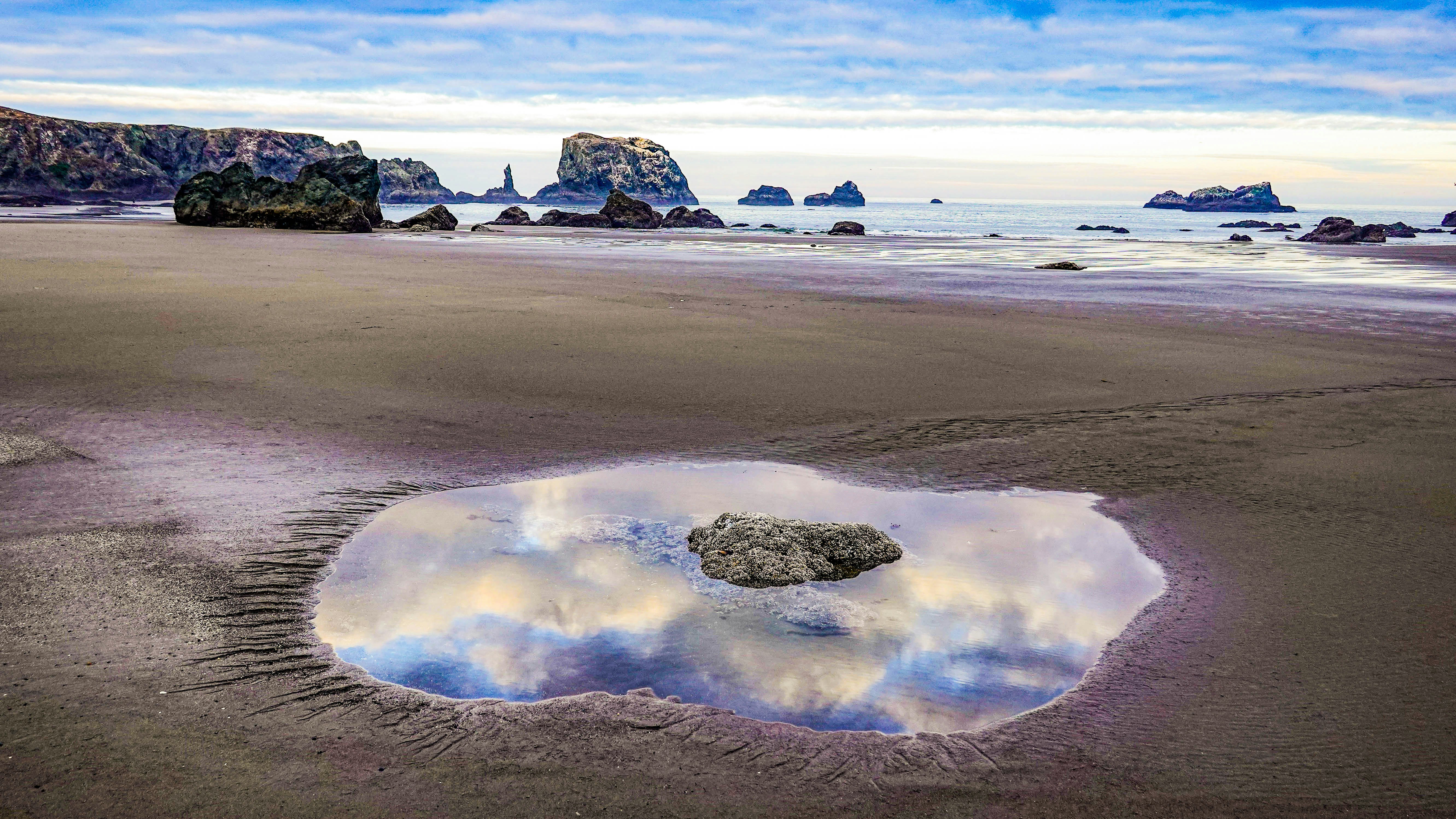 The puddle reflects the sky and distant rocks.