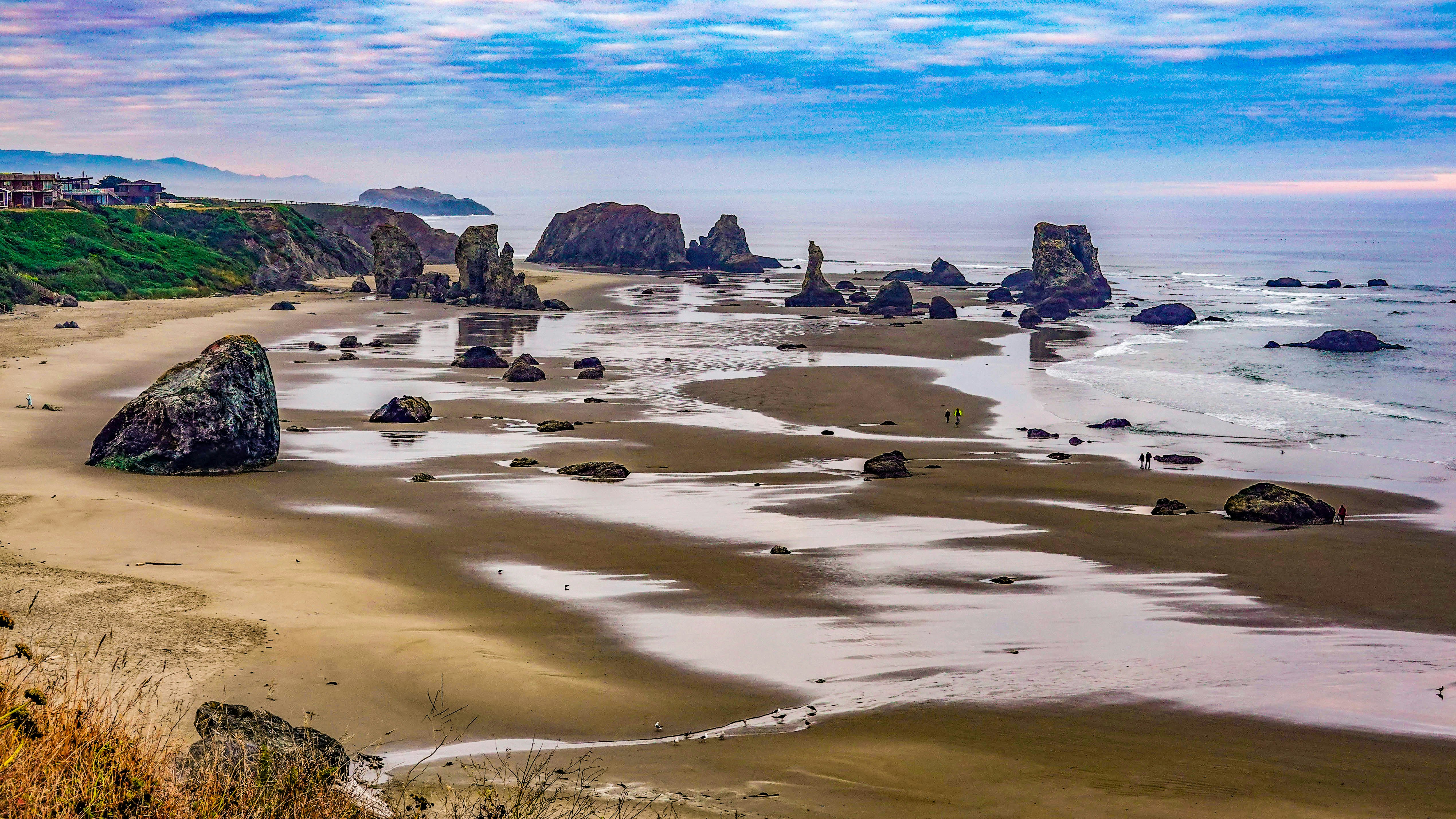 Rocky coastline with sea stacks at low tide.