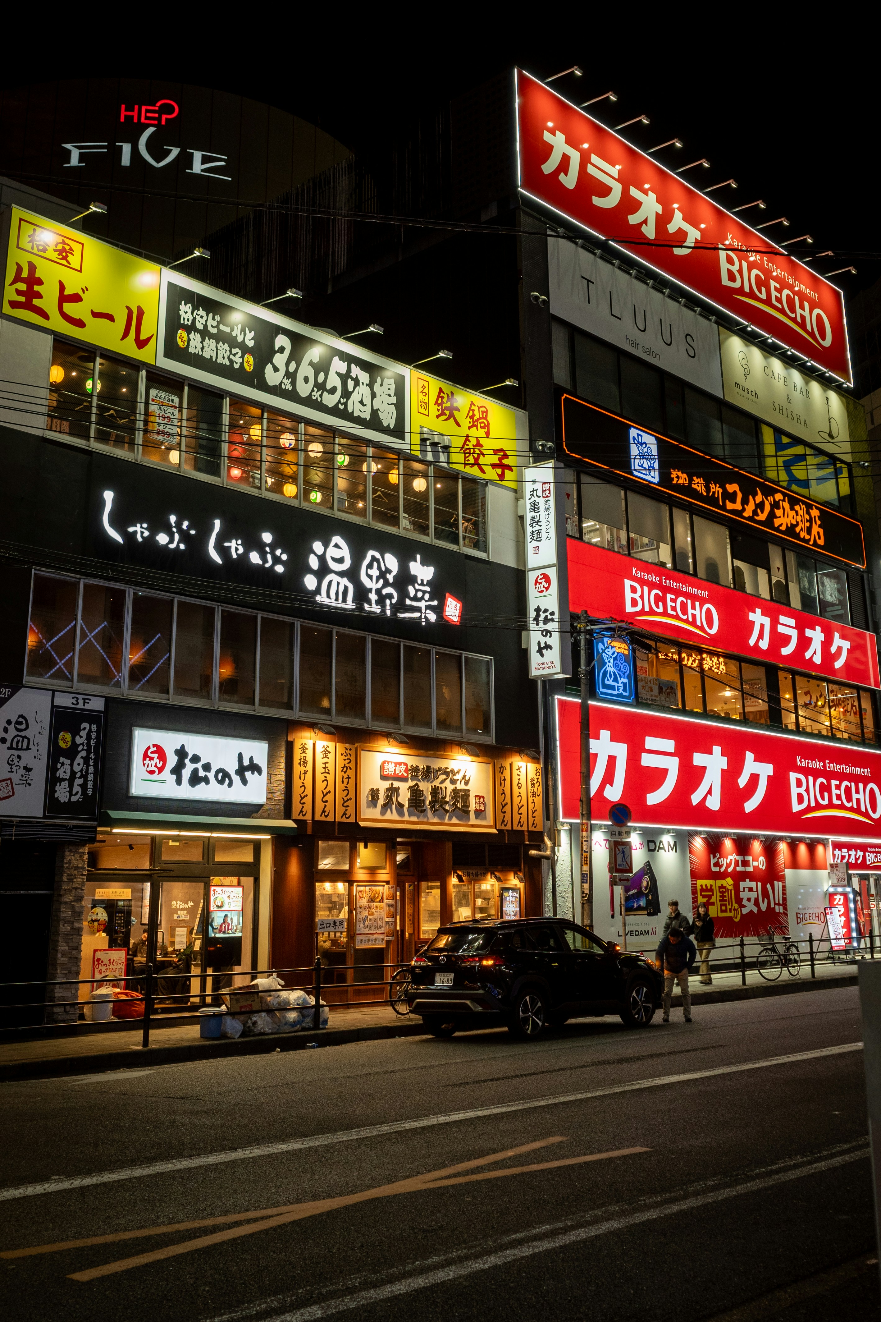 Nighttime scene of brightly lit japanese businesses.
