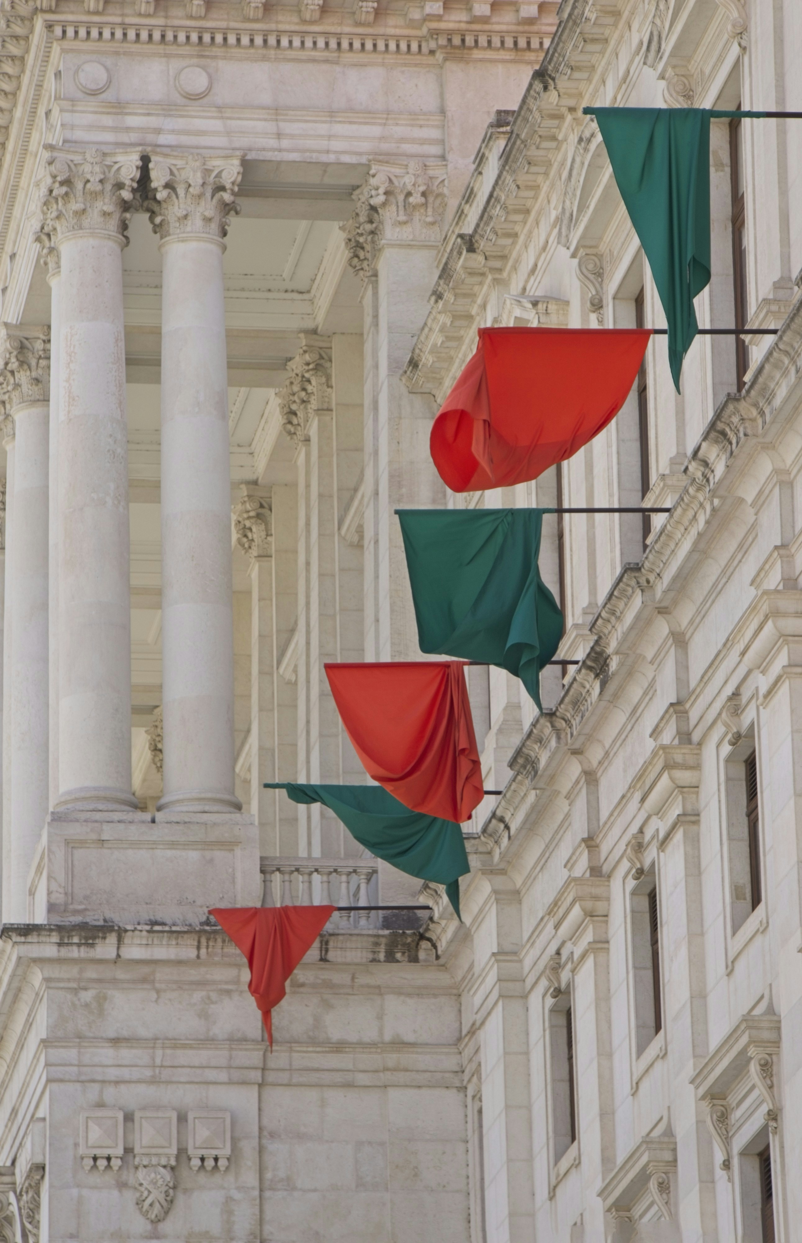 Bendera merah dan hijau tergantung di fasad bangunan.