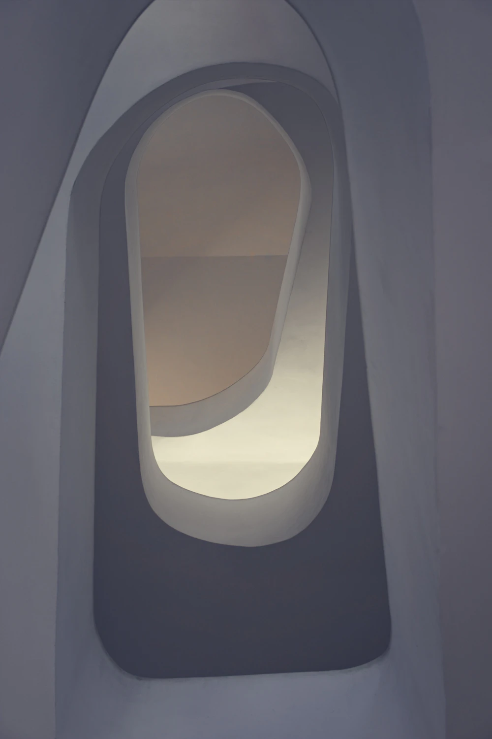 White curved walls and a stairwell filled with soft daylight