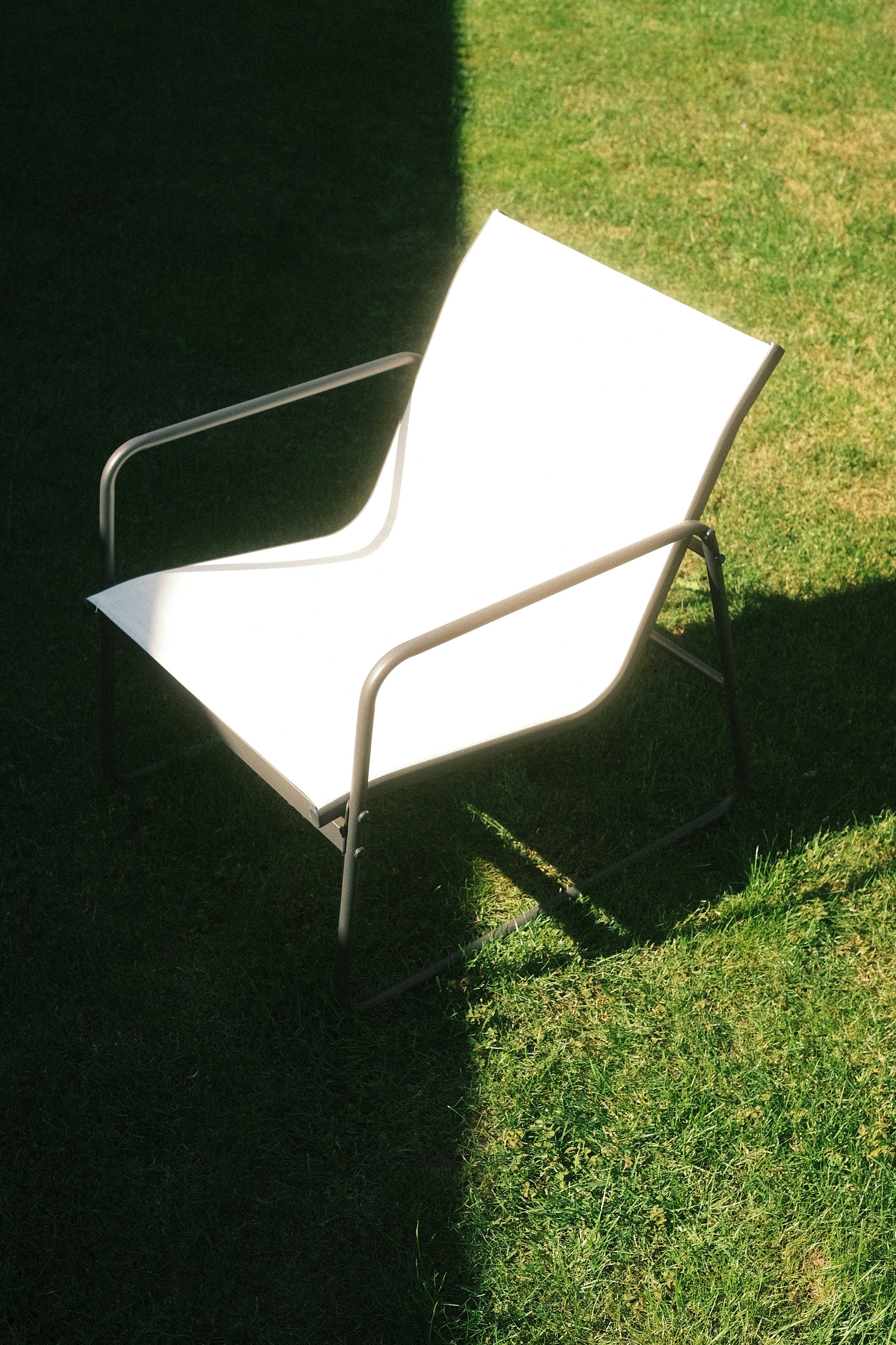 A white chair sits on a green lawn.