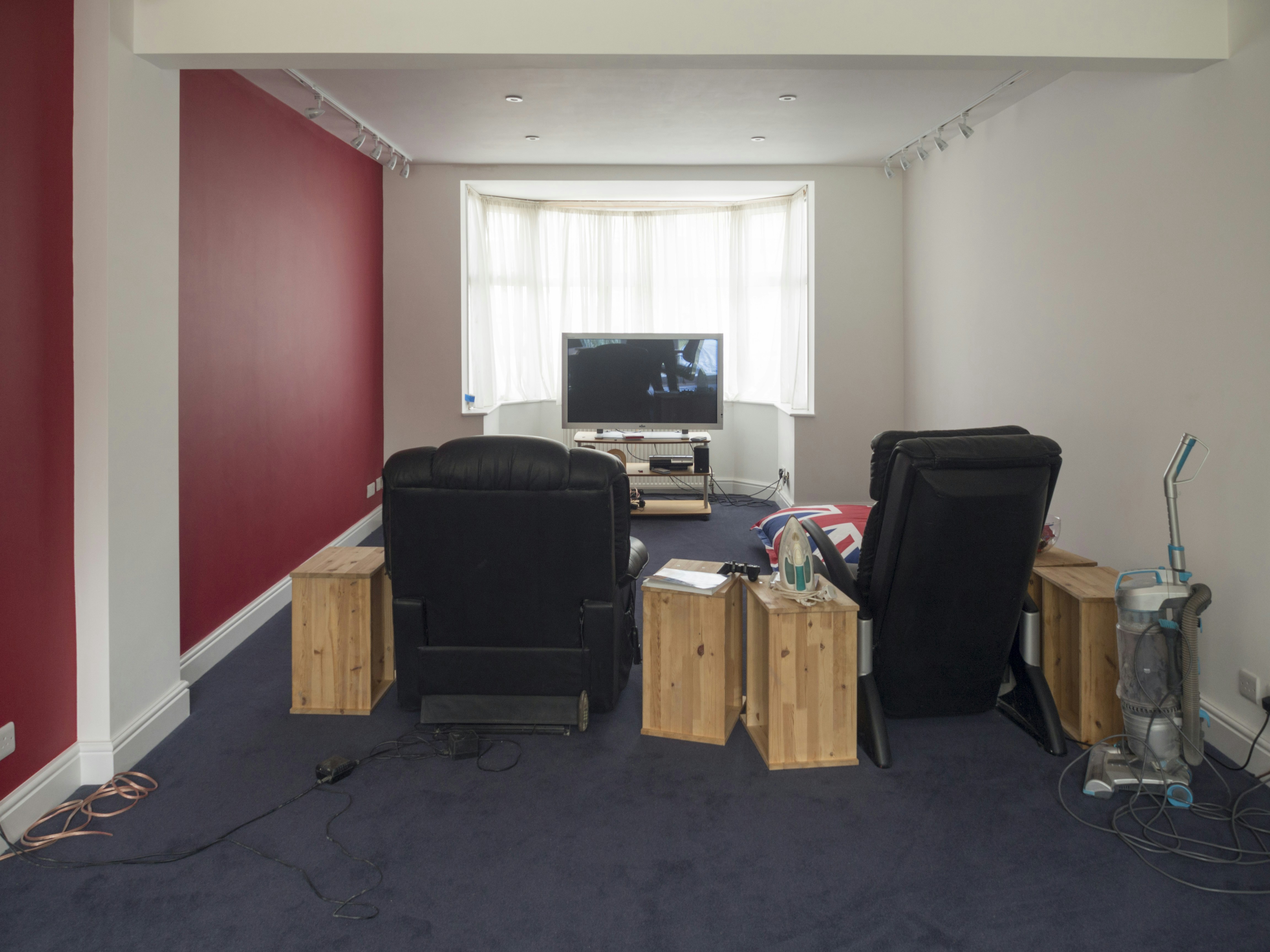 Living room with chairs, tv, and red wall.