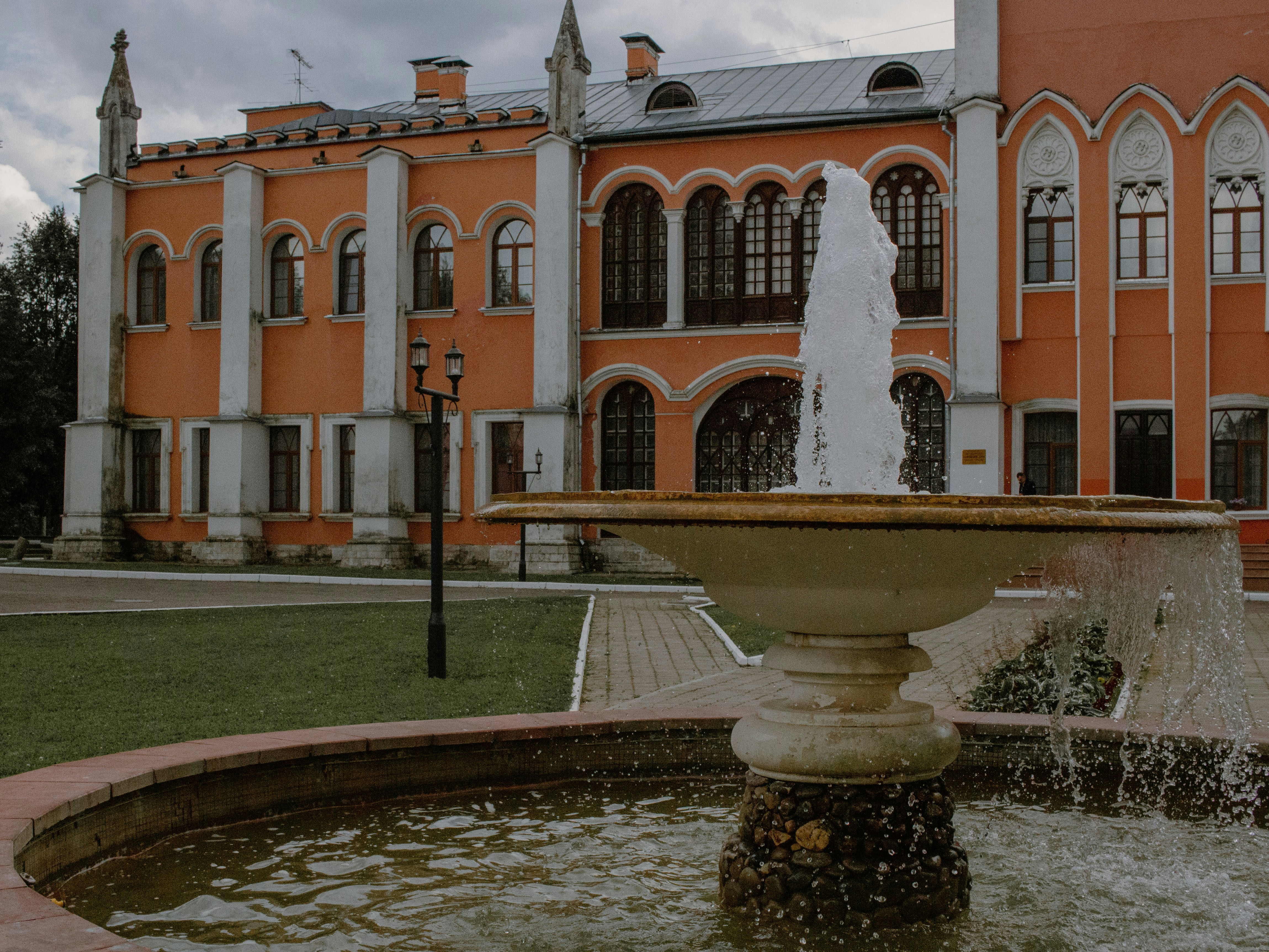 A fountain sprays in front of an ornate building.