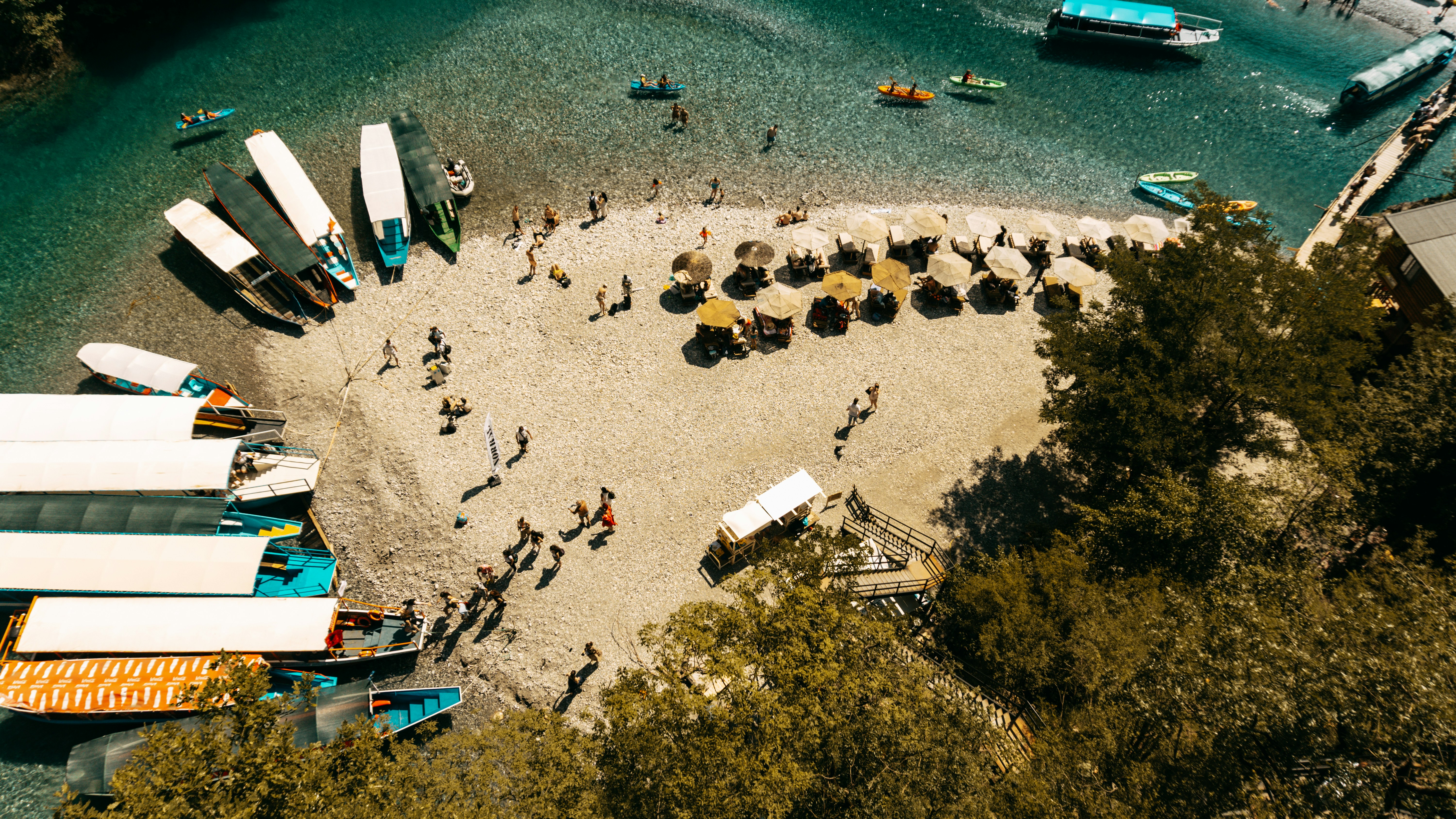 Boats, beachgoers, and umbrellas on a sandy shore.